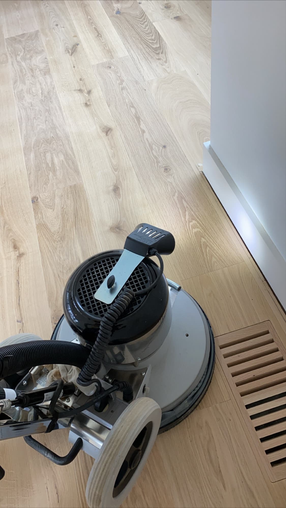 Bona PowerDrive planetary sander on white oak flooring beside a floor vent during refinishing by 12th And Oak