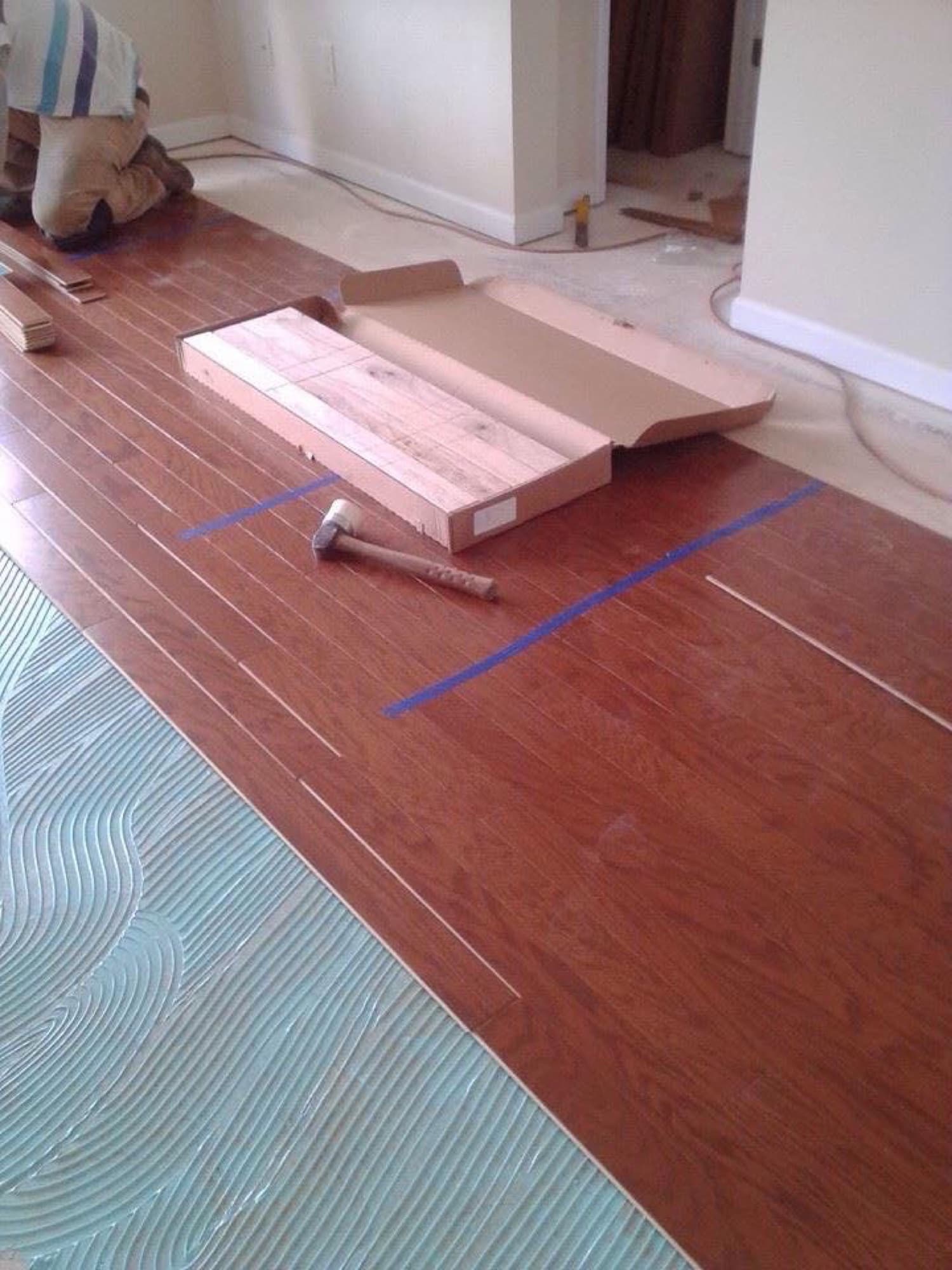 Engineered hardwood glue-down installation in progress in Fuquay-Varina NC, adhesive troweled onto the slab ahead of the prefinished planks