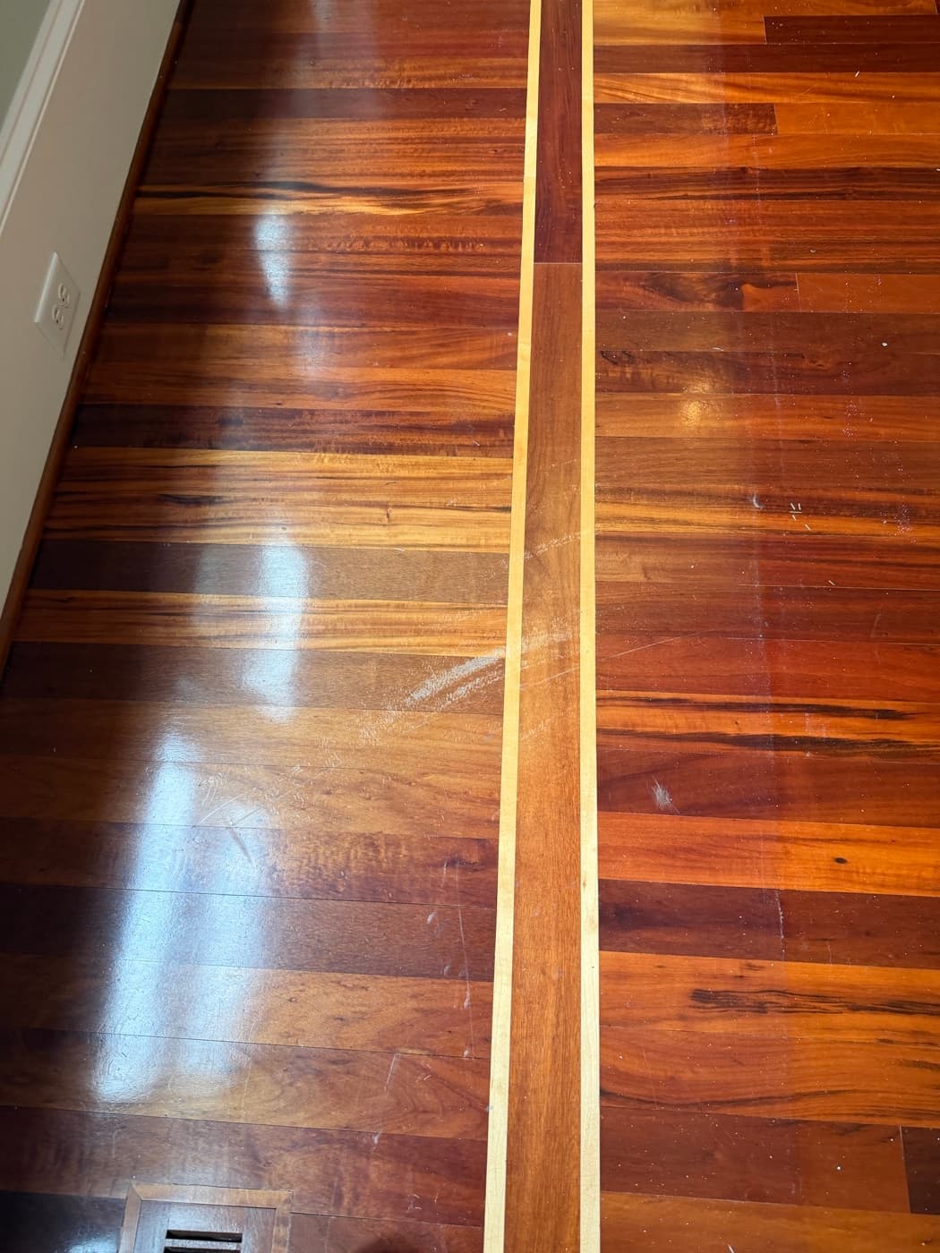 Brazilian Tigerwood hallway with hazy consumer polish buildup and visible scratches before refinishing in Glen Laurel Clayton NC