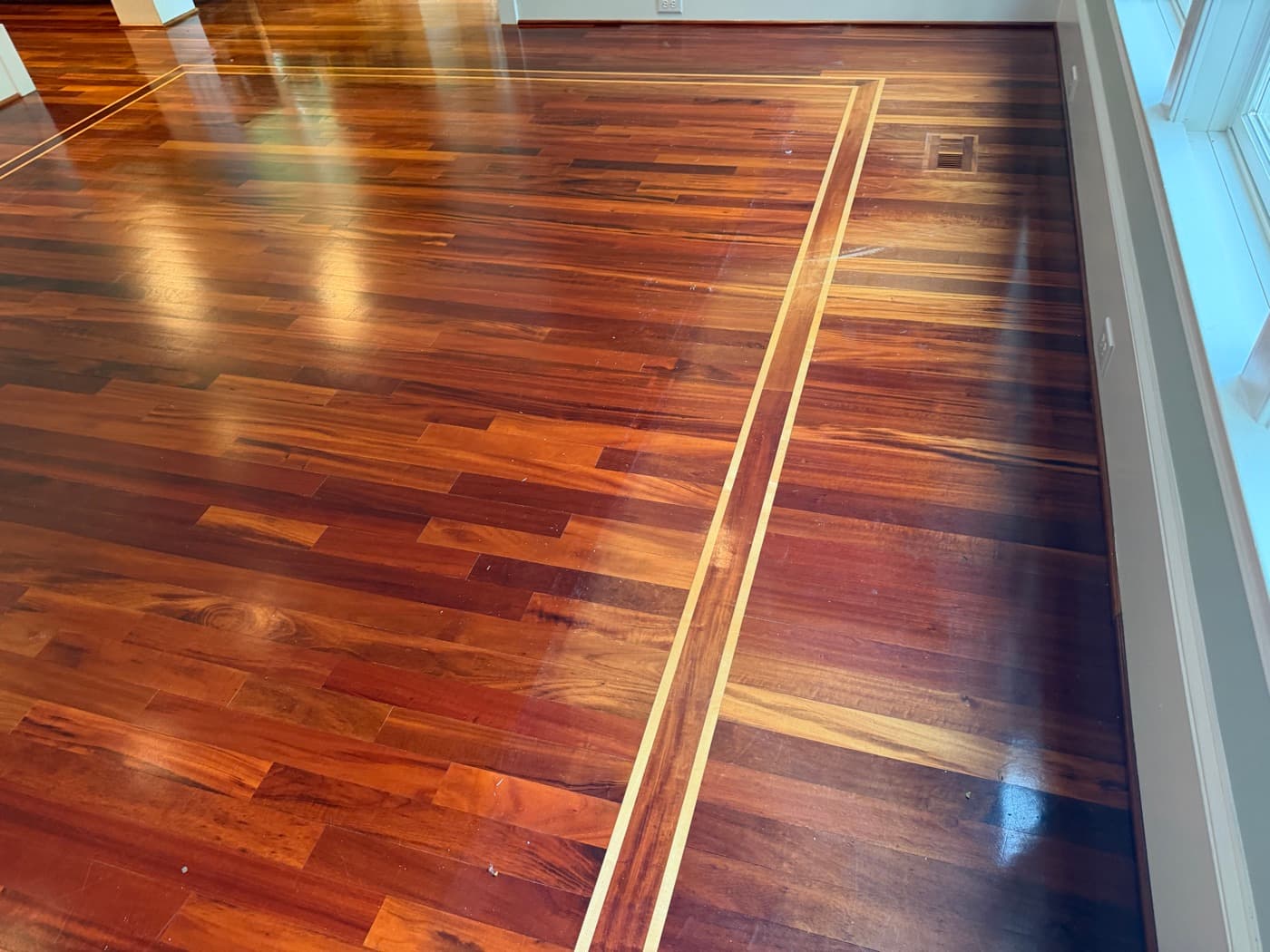 Discolored and oxidized Brazilian Tigerwood floor with uneven polish sheen before refinishing in Clayton NC