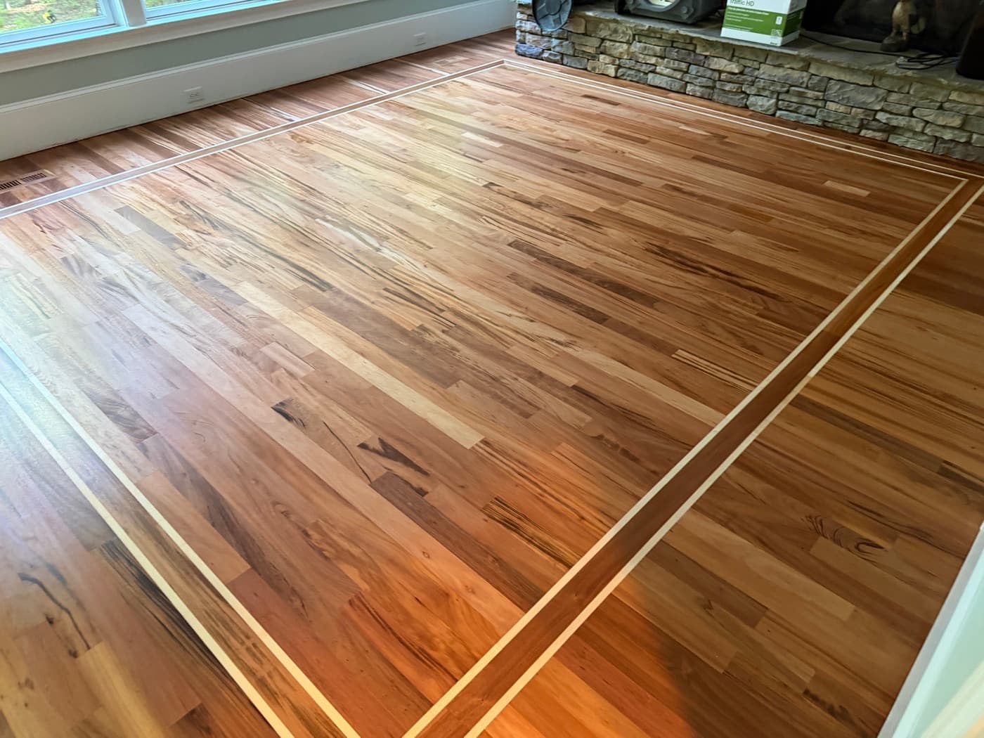 Wide view of finished Brazilian Tigerwood family room floor with maple inlay borders in Clayton NC