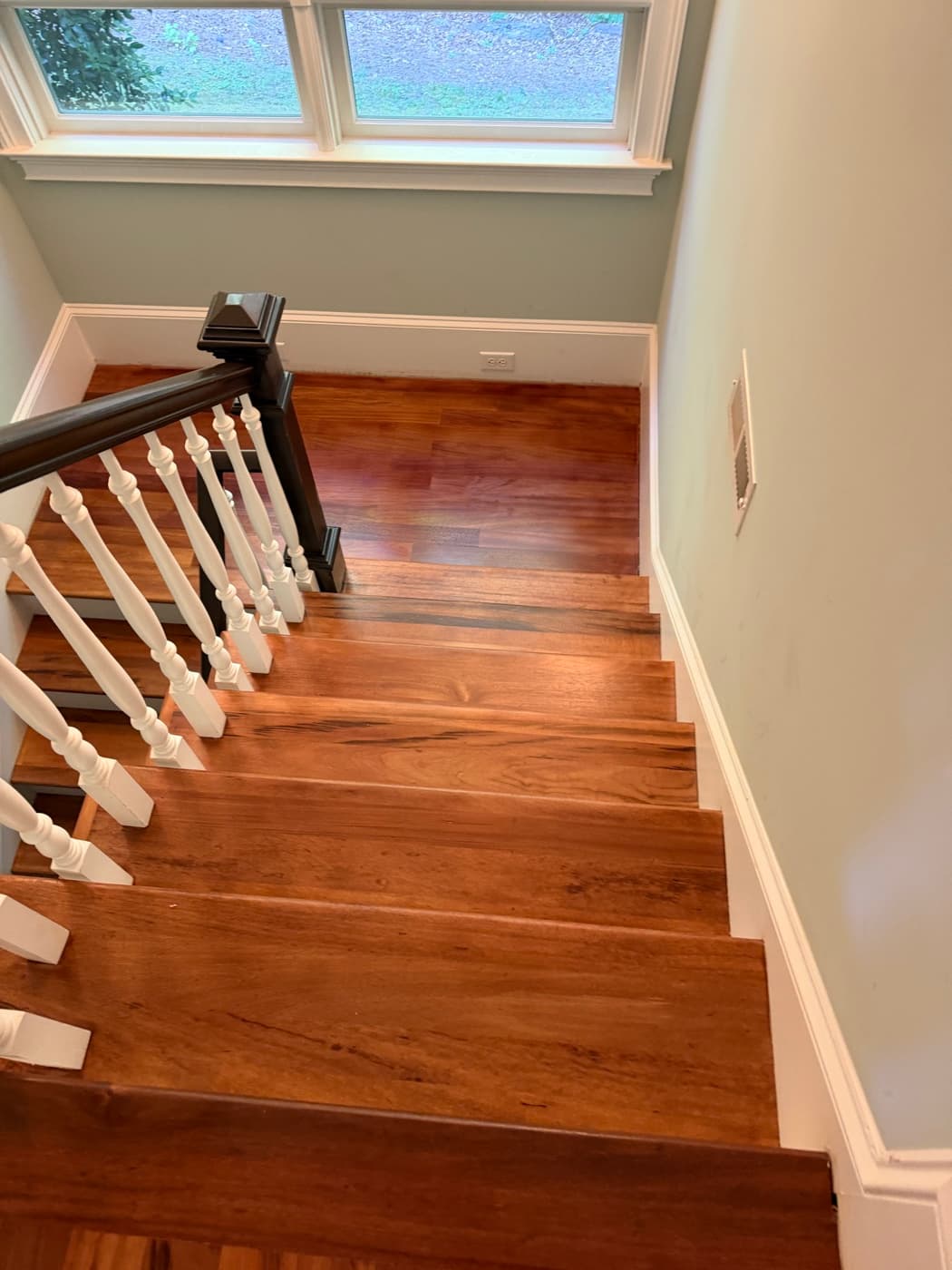 Refinished Brazilian Tigerwood staircase treads looking down toward landing window in Glen Laurel Clayton NC