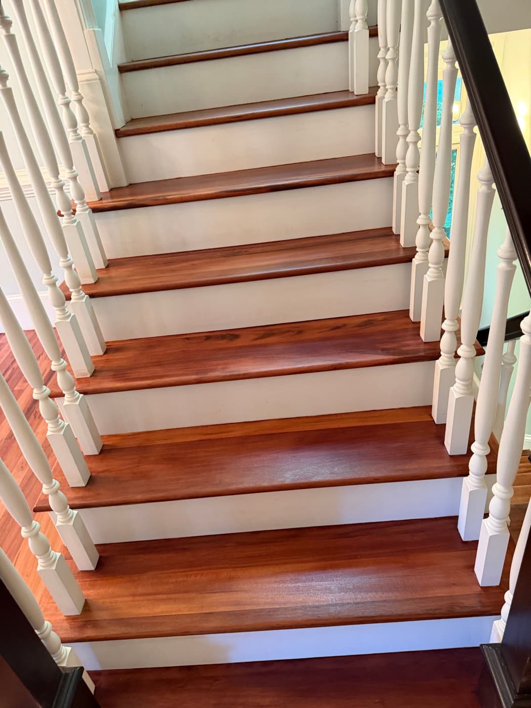 Refinished Brazilian Tigerwood staircase treads with white risers looking up in Clayton NC