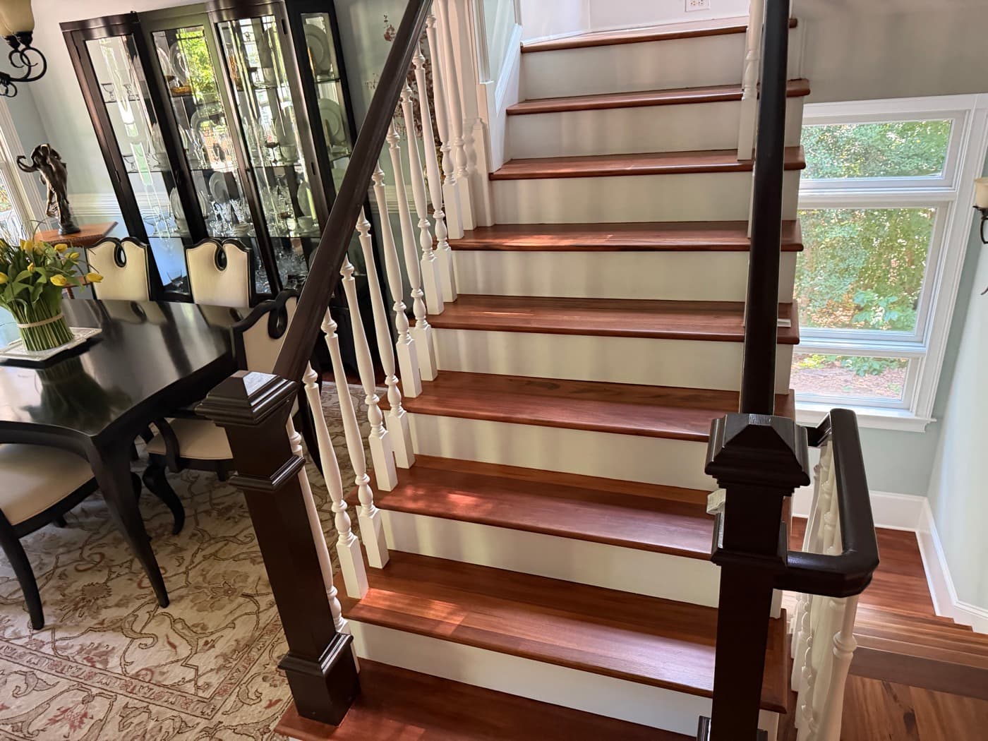 Refinished Brazilian Tigerwood staircase with white balusters and dark rail in furnished Glen Laurel home Clayton NC