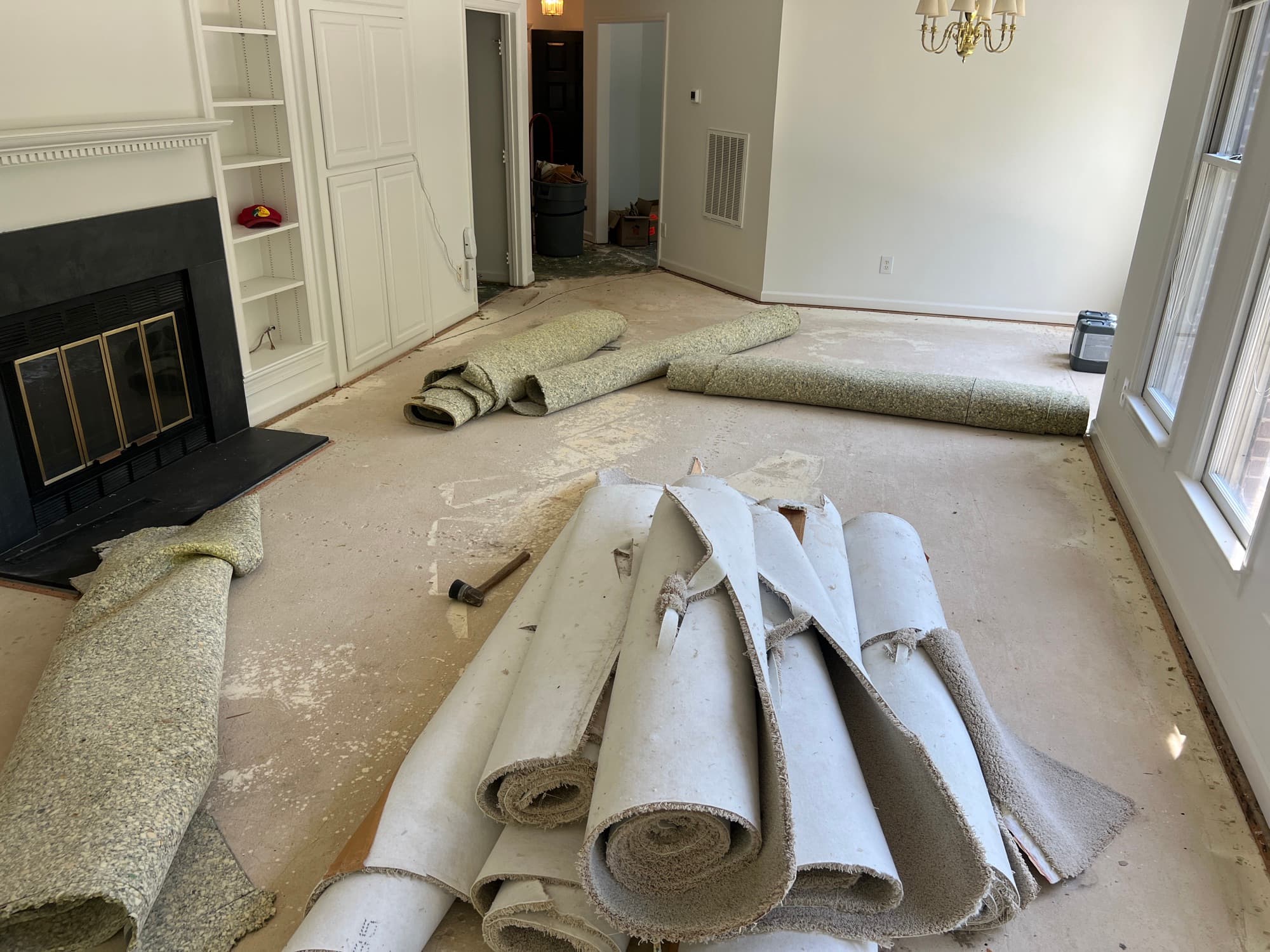 Carpet and pad rolled up during demo in living room with fireplace, Downtown Raleigh
