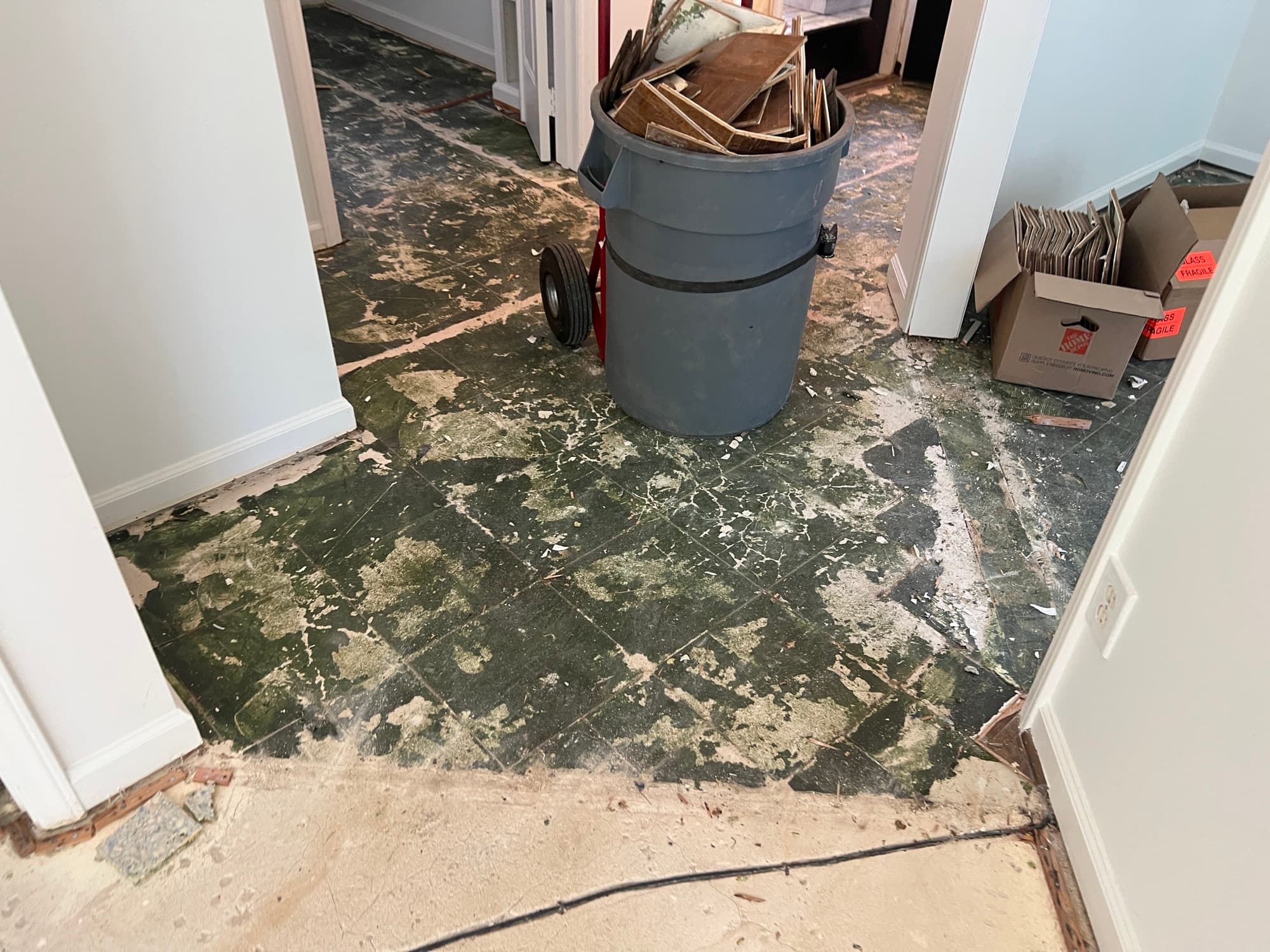 Old cutback adhesive exposed on concrete slab after parquet removal in hallway