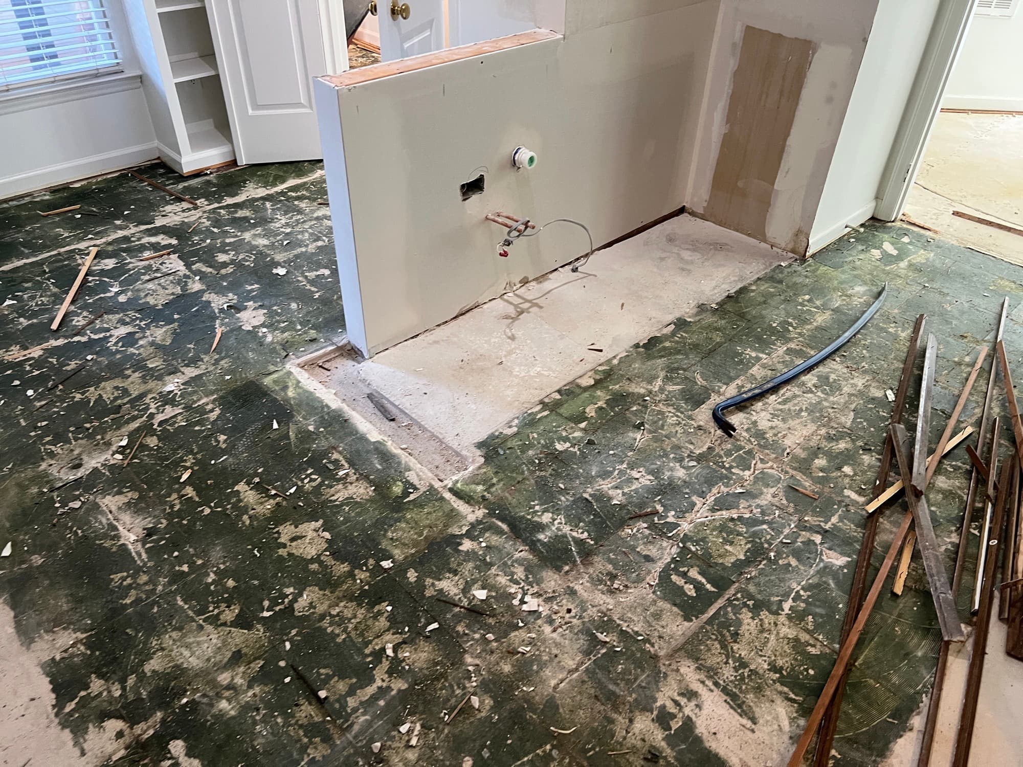 Kitchen concrete slab during demo with adhesive residue before self-leveling
