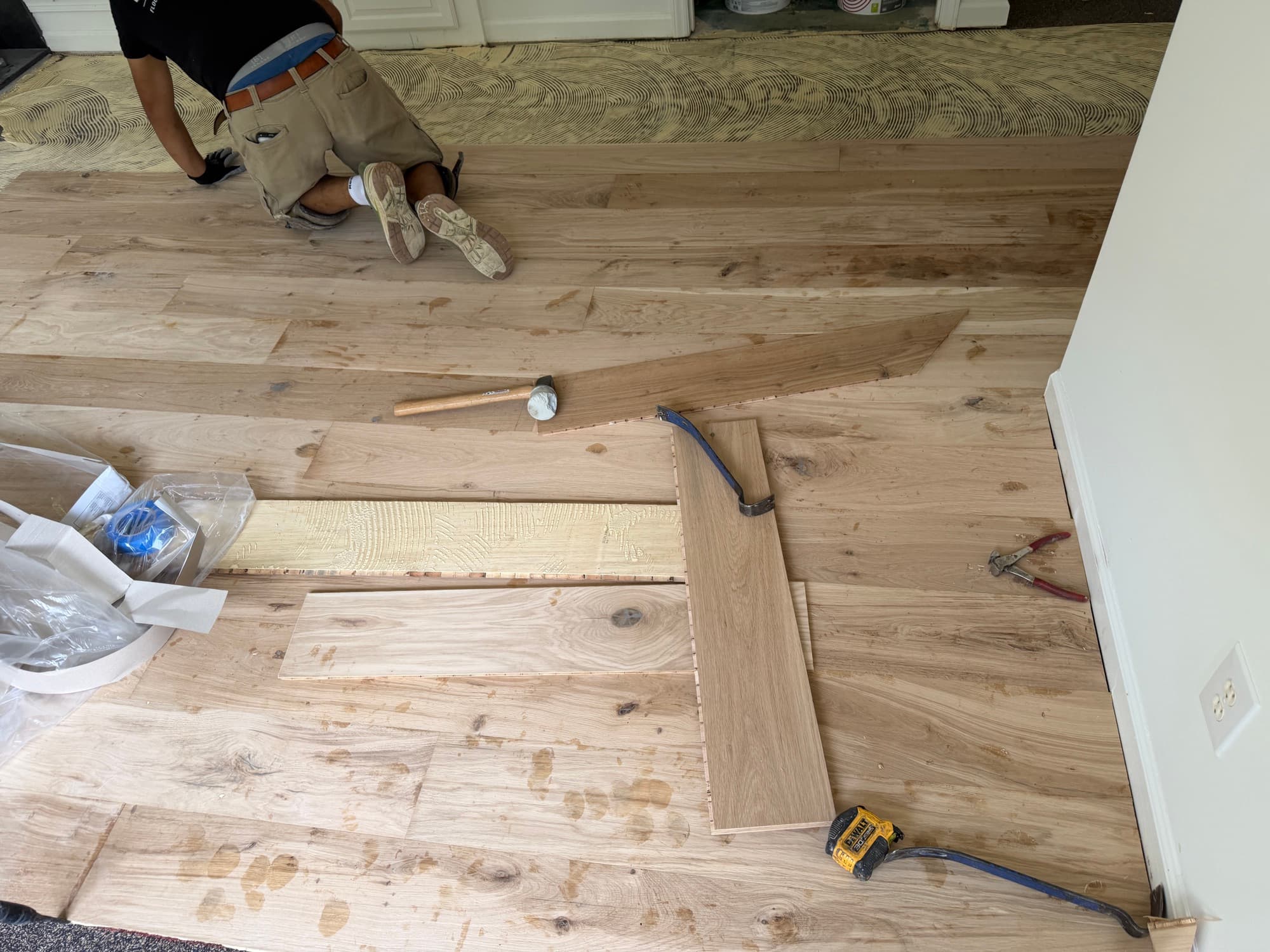 Installer racking character grade European white oak planks during glue-down installation