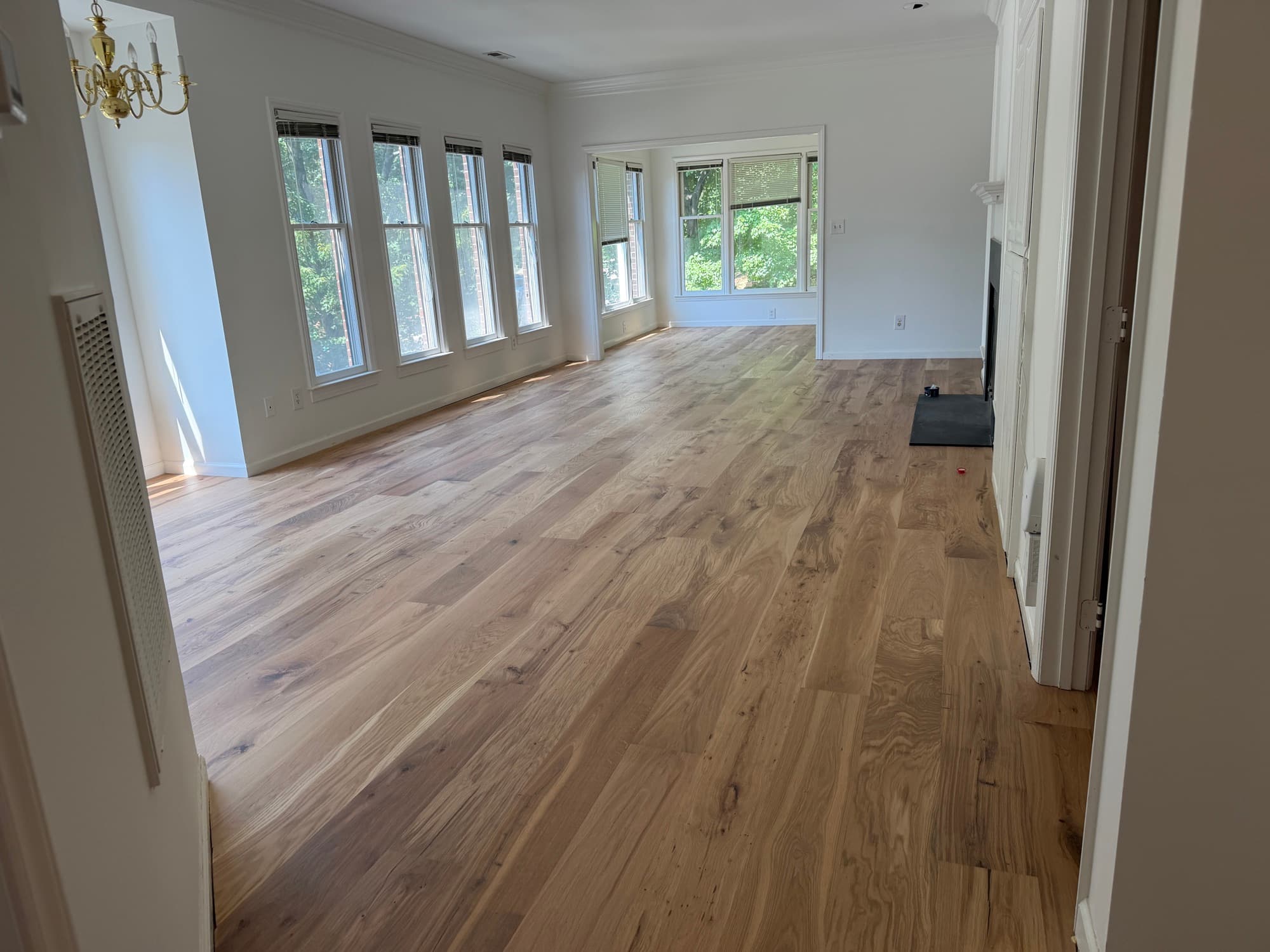 Hallway opening into living room with continuous wide plank white oak flooring