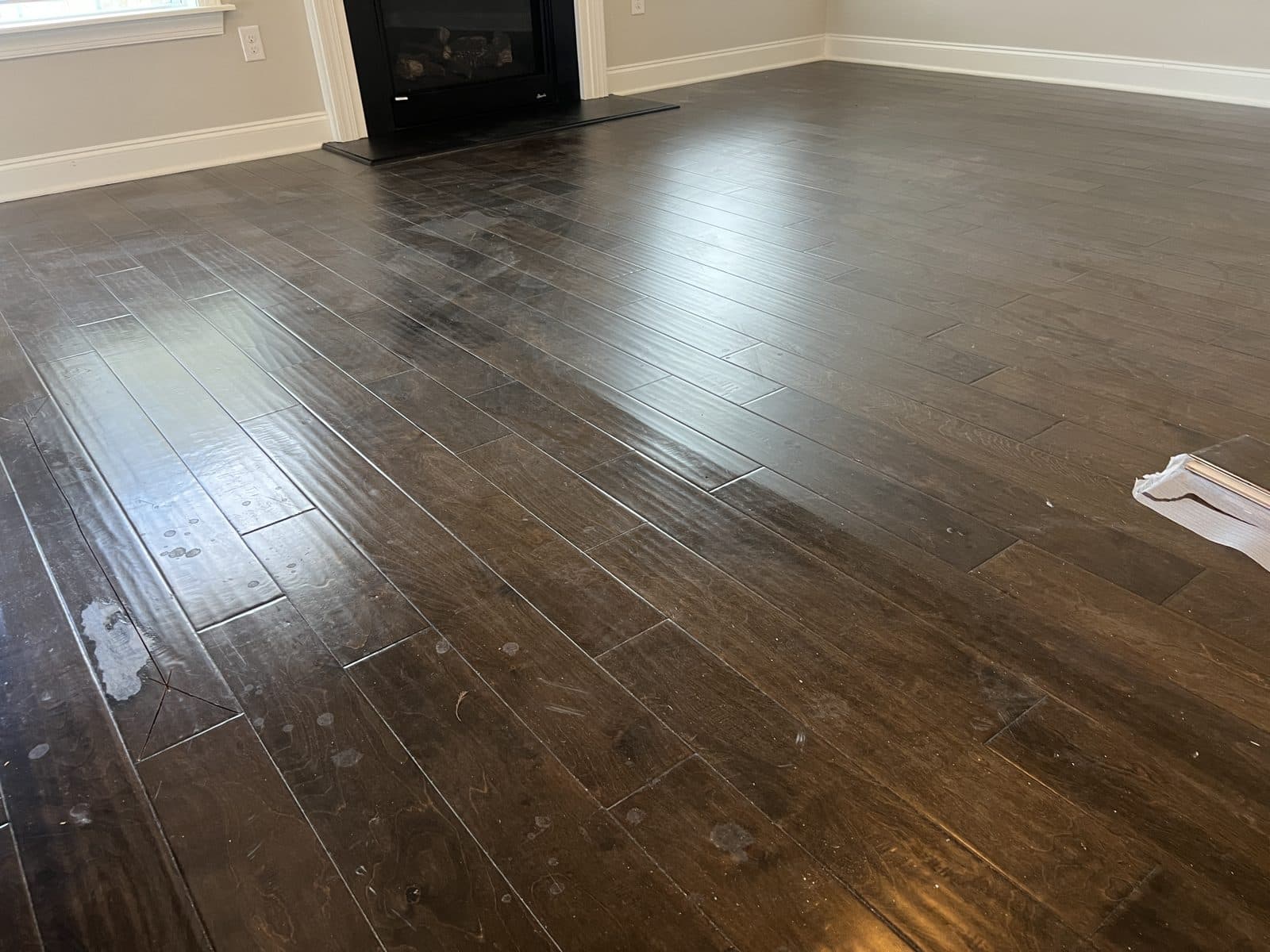Hand-scraped engineered floor with hazy polish film and white drip marks before polish removal in Fuquay-Varina NC
