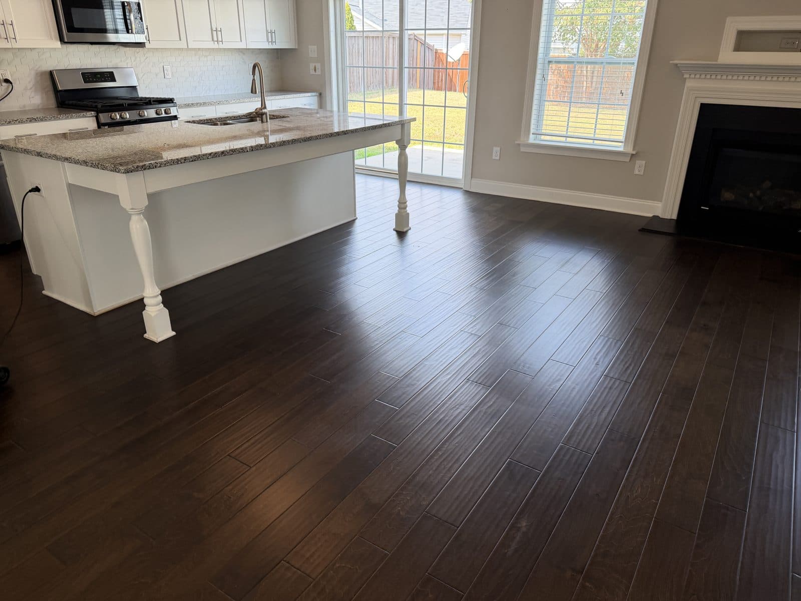 Hand-scraped dark engineered hardwood floor in Fuquay-Varina NC after polish removal and deep clean, kitchen island and living room with even low sheen