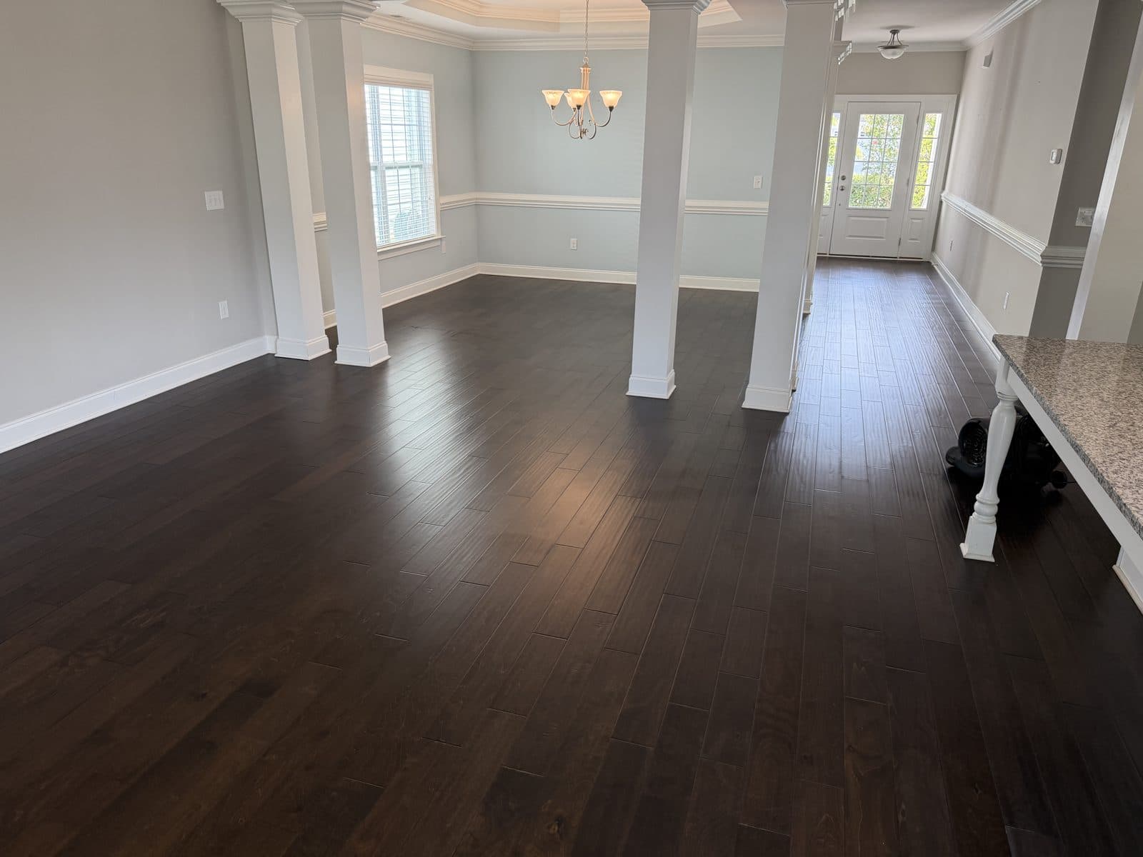 Dining room and foyer with columns, dark hand-scraped engineered floor after deep clean in Fuquay-Varina NC