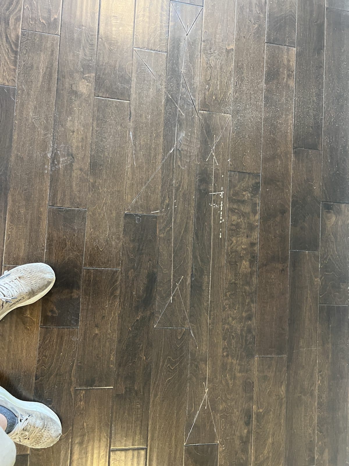 Several damaged hand-scraped engineered boards marked with tape for replacement in Fuquay-Varina NC