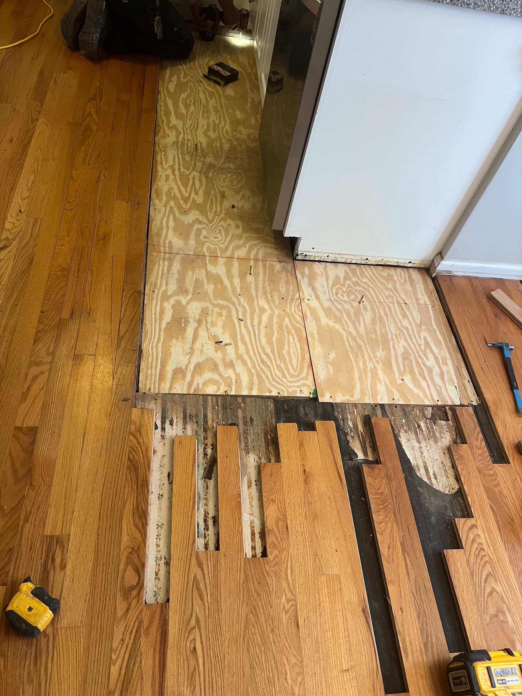New plywood subfloor repair patched in and new red oak boards beginning installation in Matthews Farm Clayton NC kitchen