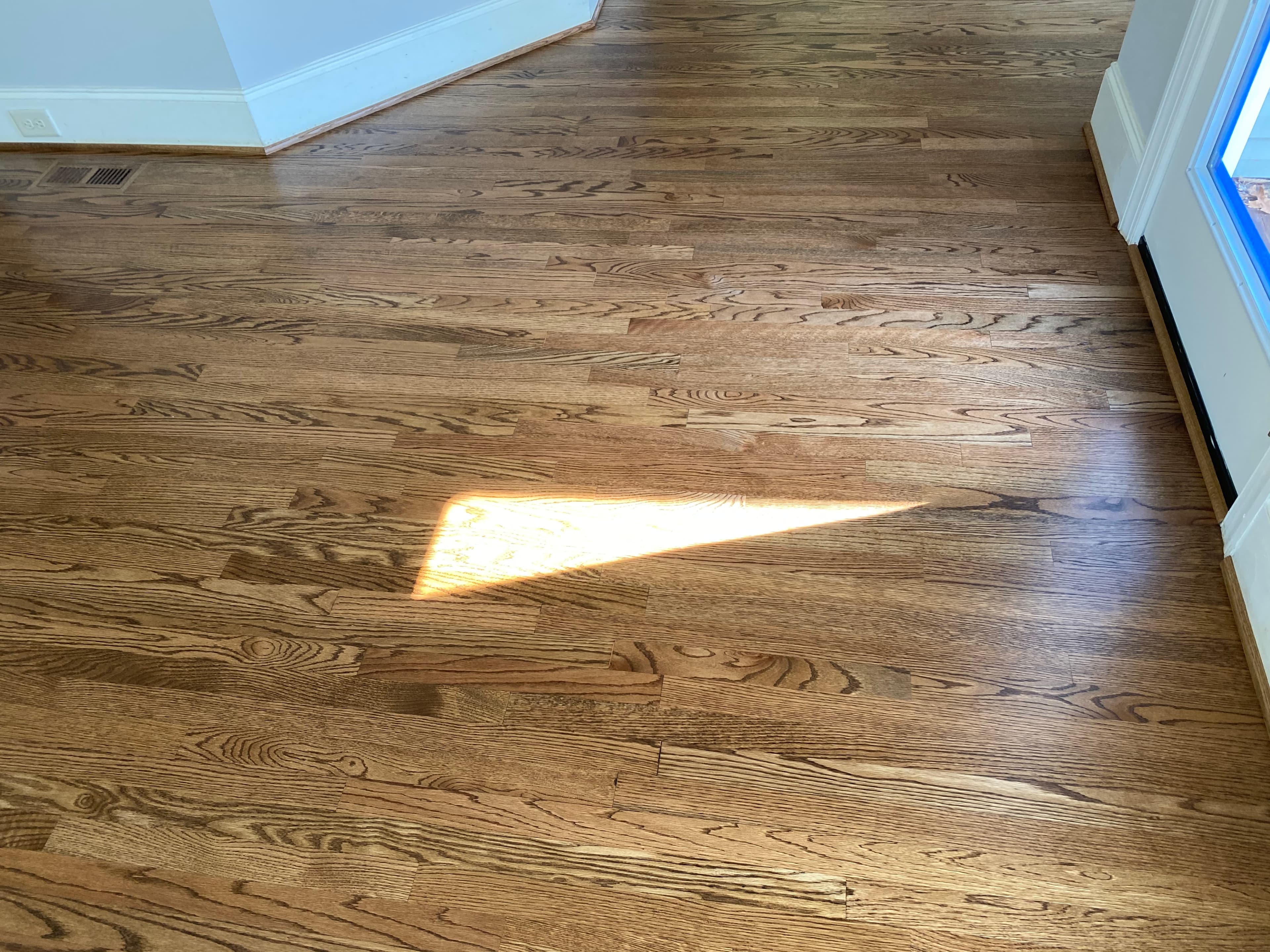 Finished 3.25 inch red oak floors after seamless water damage repair and full refinish in Hocutt Farm Flowers Plantation Clayton NC, back door area indistinguishable from original floor