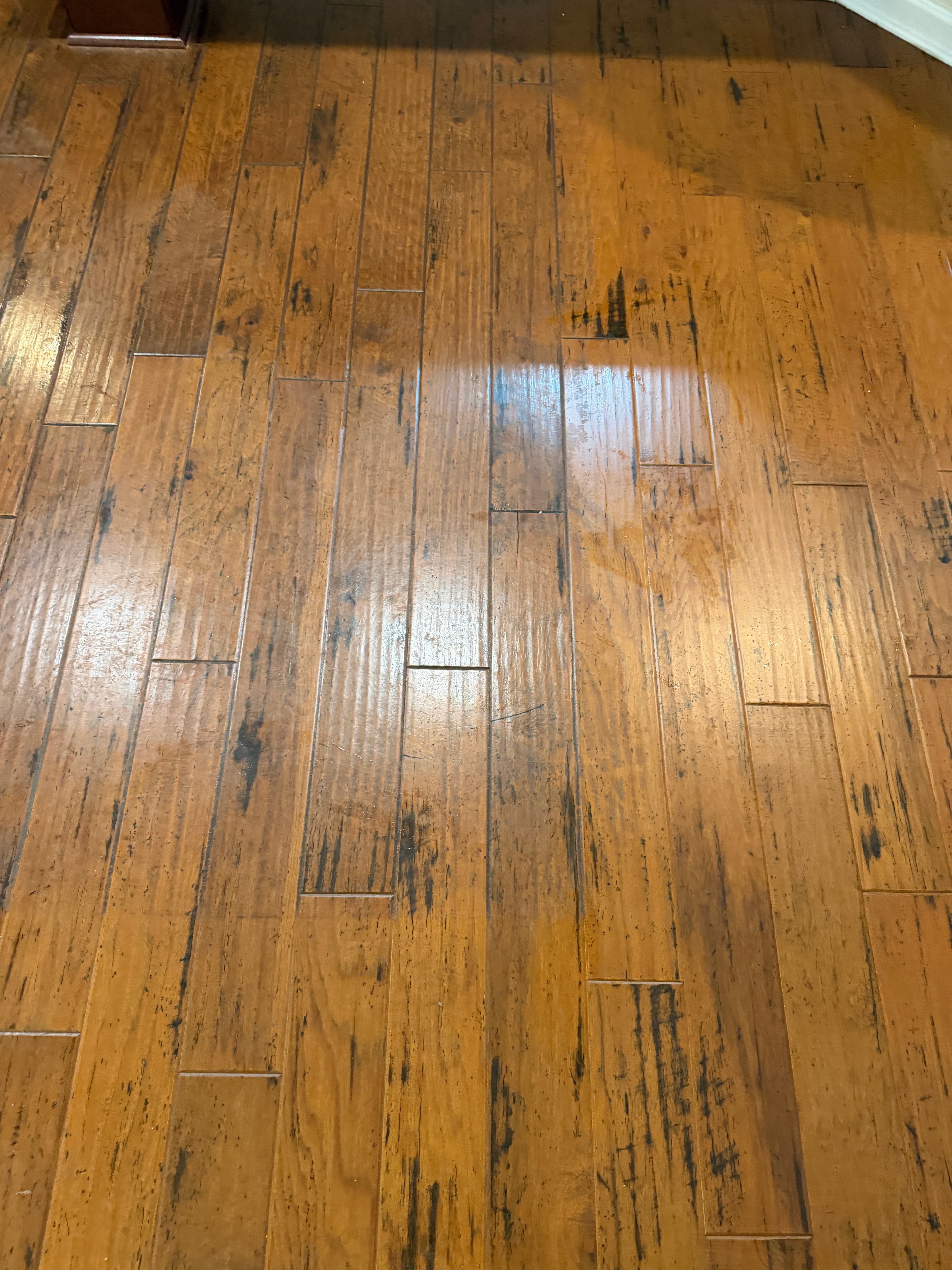 Hand-scraped hickory floor with hazy consumer polish buildup before deep clean in Holly Springs NC