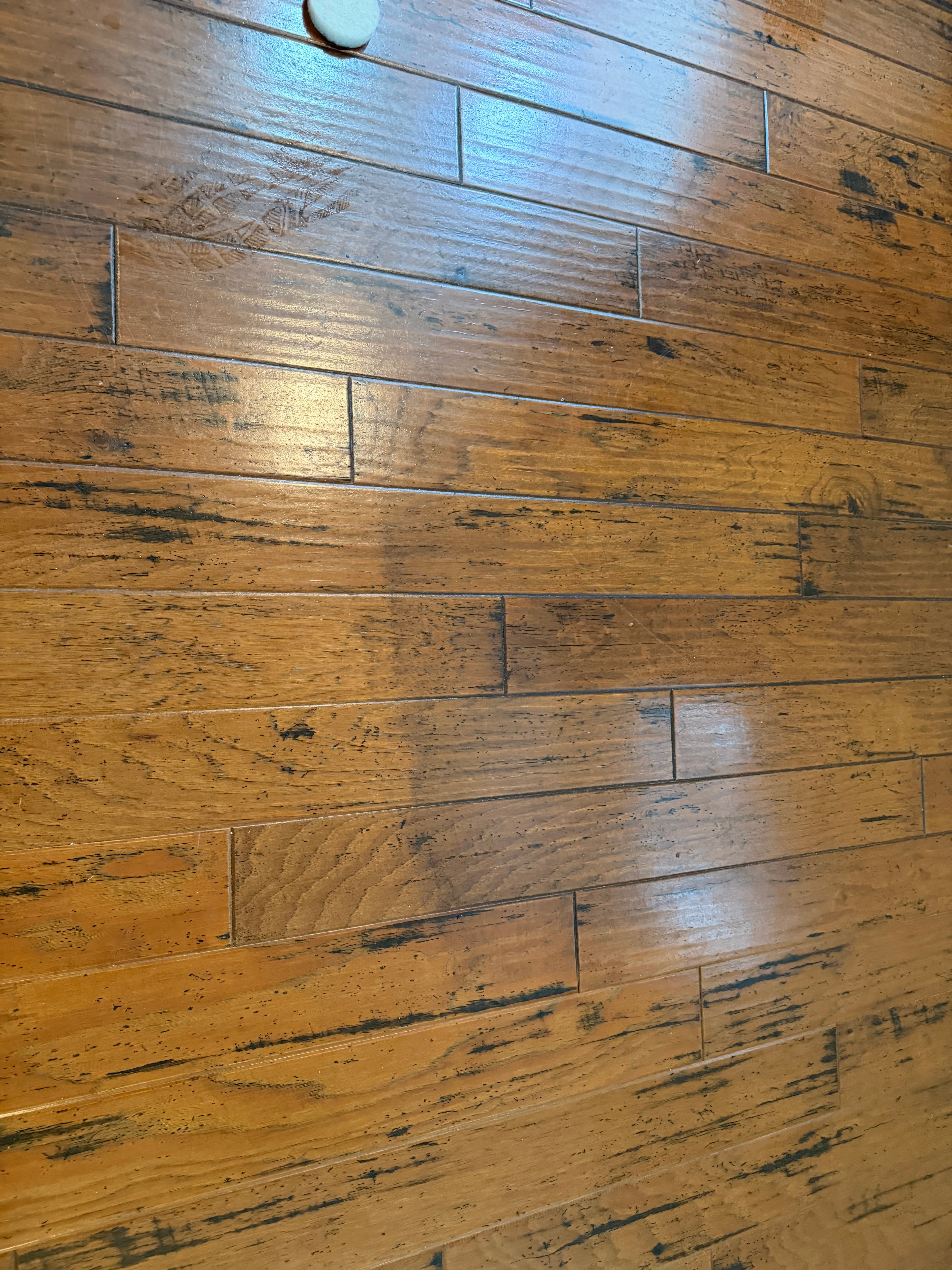 Grime and polish embedded in beveled edges of hand-scraped hickory flooring before cleaning in Holly Springs NC