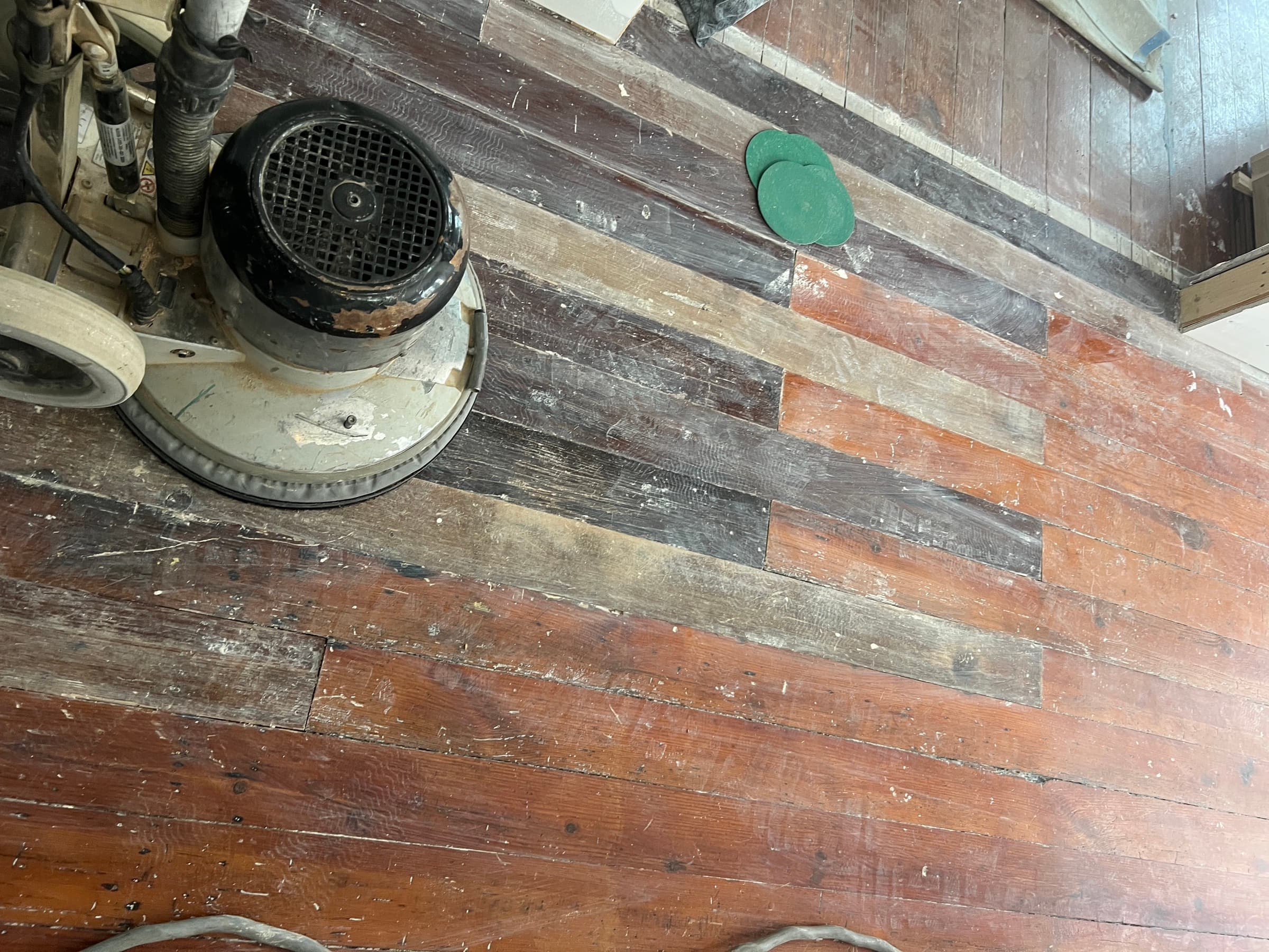 Heart pine floor showing board replacement work beginning in Morrisville NC, original finish and salvaged patch boards visible