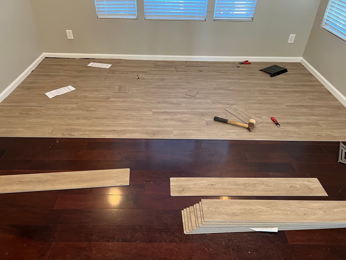 LVP planks being installed over dark engineered hardwood in living room of Garner NC townhouse, installation in progress