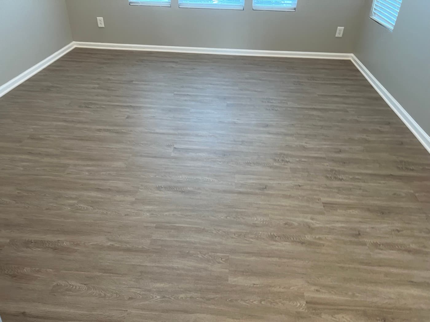 Finished gray LVP flooring in living room of Miriah Towns townhouse, Garner NC, empty room with triple windows