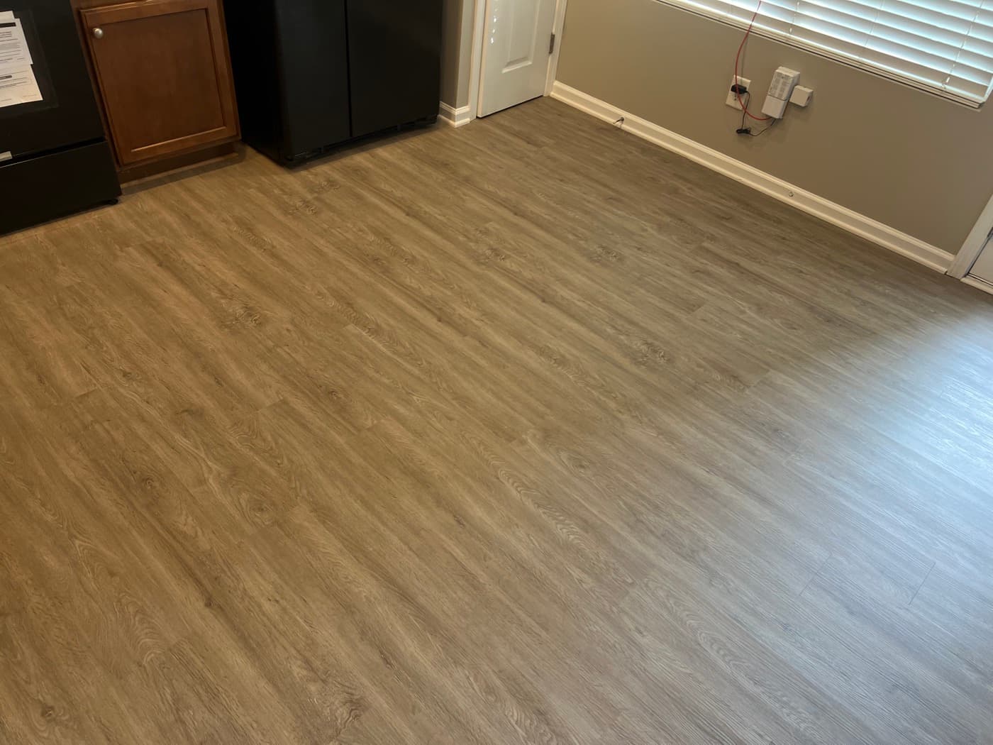 Finished LVP flooring in kitchen and dining area of Garner NC townhouse with black appliances