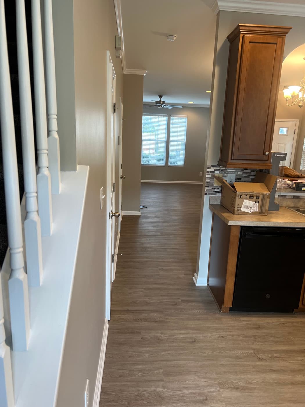 Finished LVP flooring viewed from staircase landing in open plan Garner NC townhouse, kitchen and living area visible