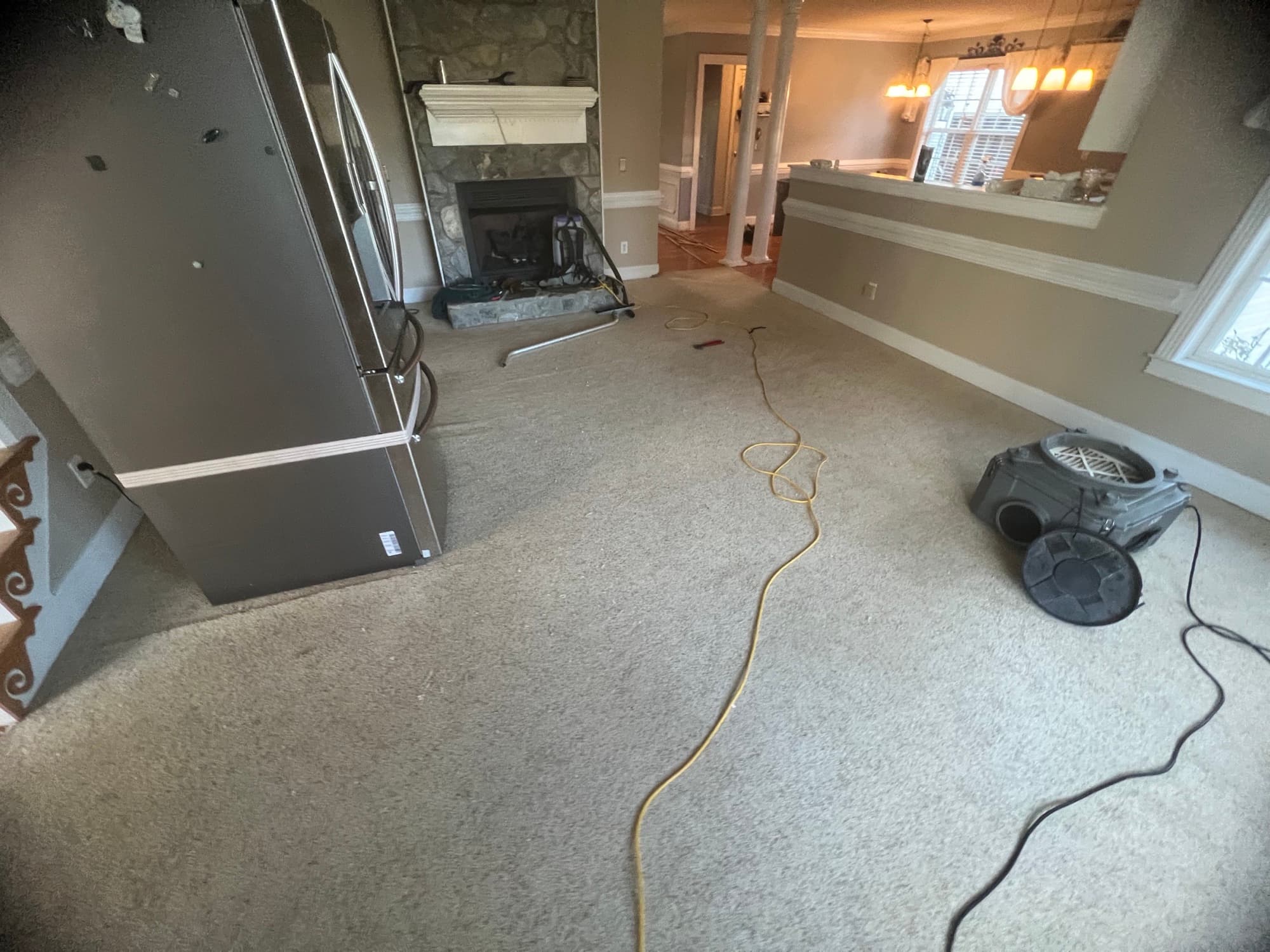 Living room with carpet and stone fireplace before LVP installation in Winston Plantation Clayton NC