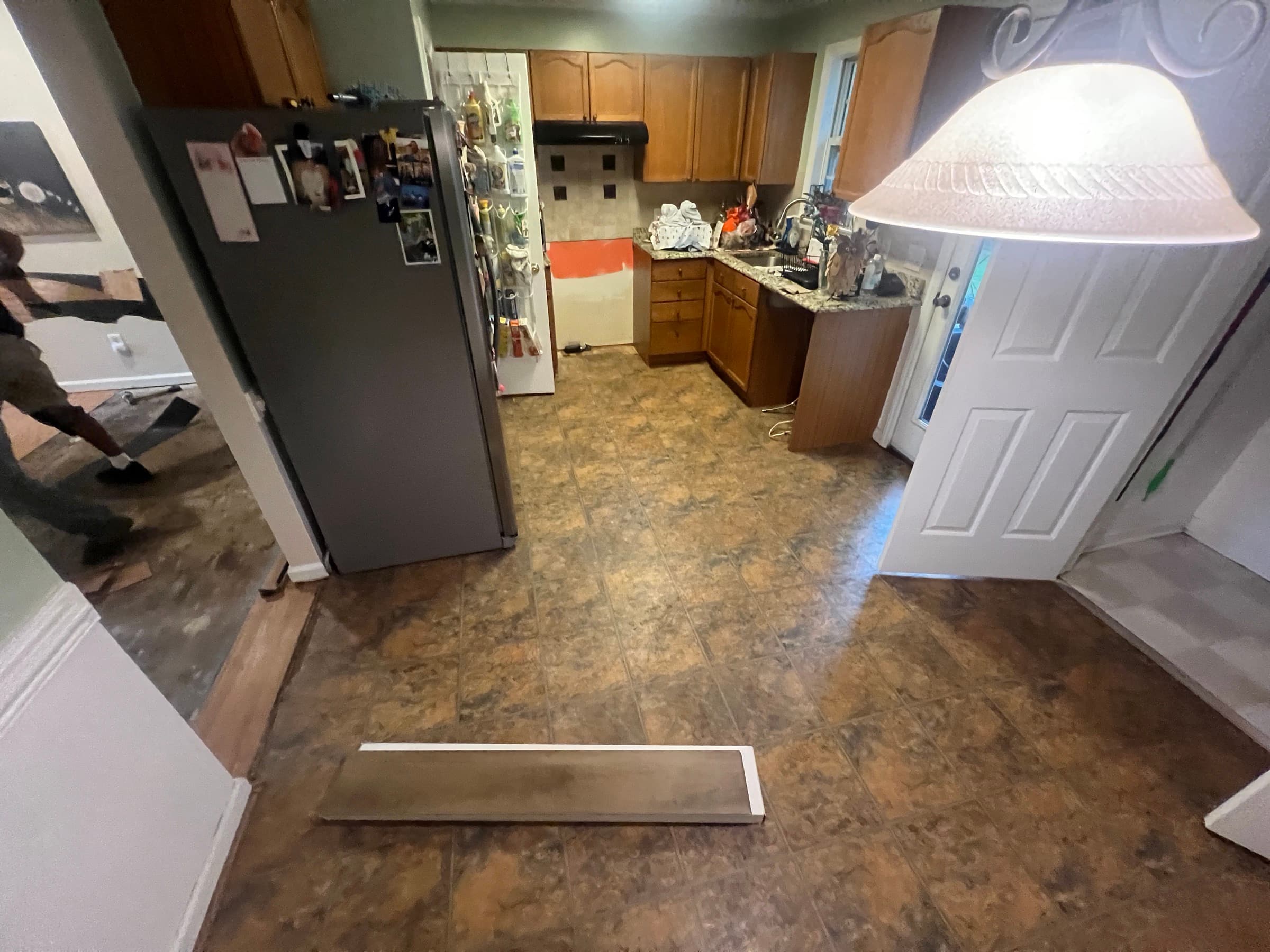 Original vinyl tile in kitchen and laminate in adjacent rooms before LVP installation in Zebulon NC home