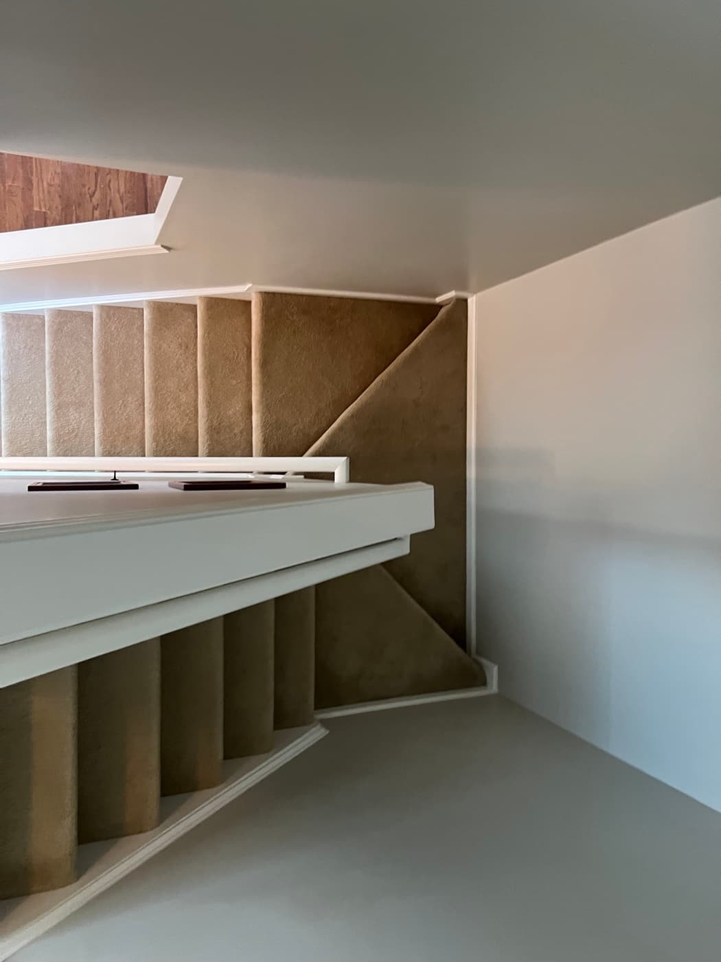 Full carpeted staircase before LVP remodel in Tuscany Clayton NC, worn tan carpet on L-shaped stairs