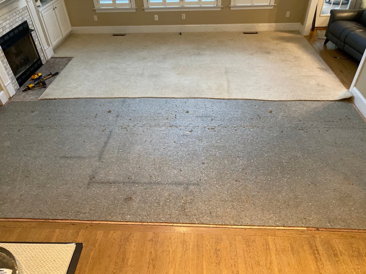 Carpet pulled up from family room exposing subfloor before hardwood installation in Glen Laurel Clayton NC