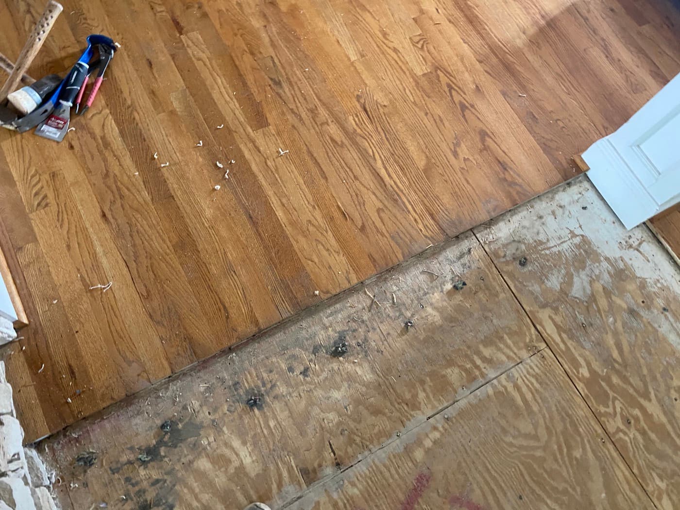 Existing red oak hardwood floor at transition to bare plywood subfloor showing lace-in starting point at Sunset Lakes Fuquay-Varina NC