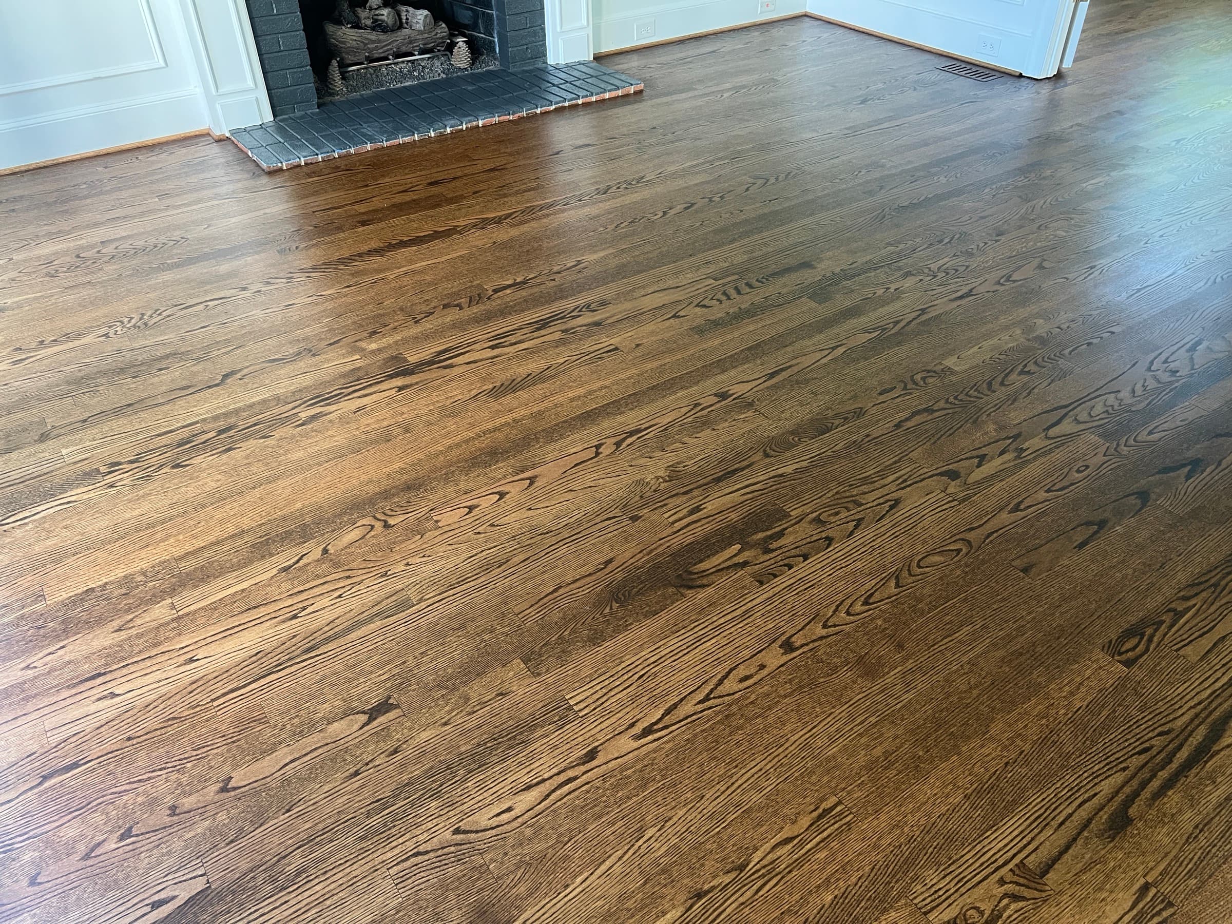 Finished red oak floors after installation and staining in Umstead Ridge Raleigh NC, DuraSeal Medium Brown grain detail with fireplace