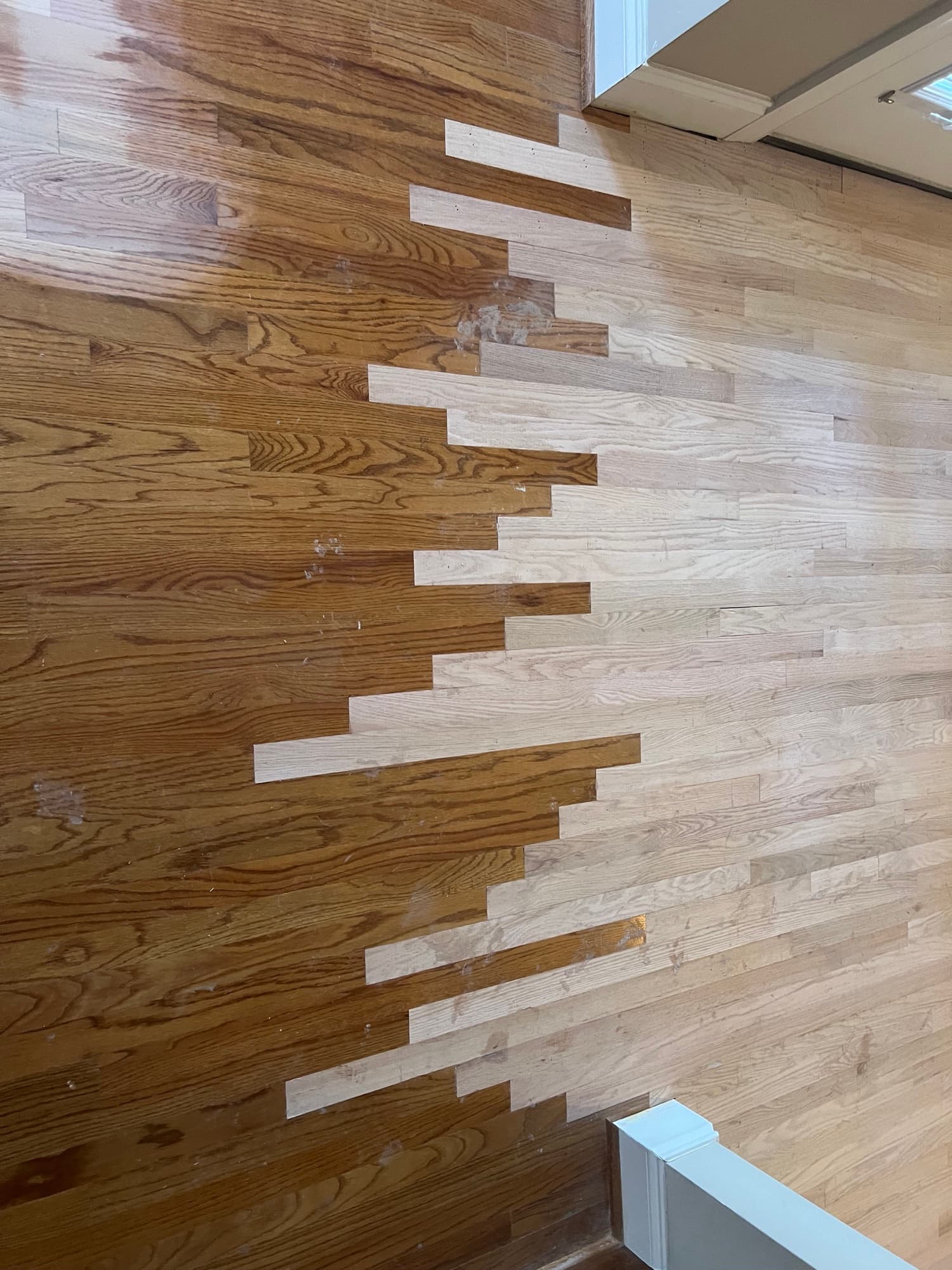 Red oak lace-in seam in progress in Summerset Place Clayton NC, old finished boards left meeting new unfinished boards right in staggered pattern