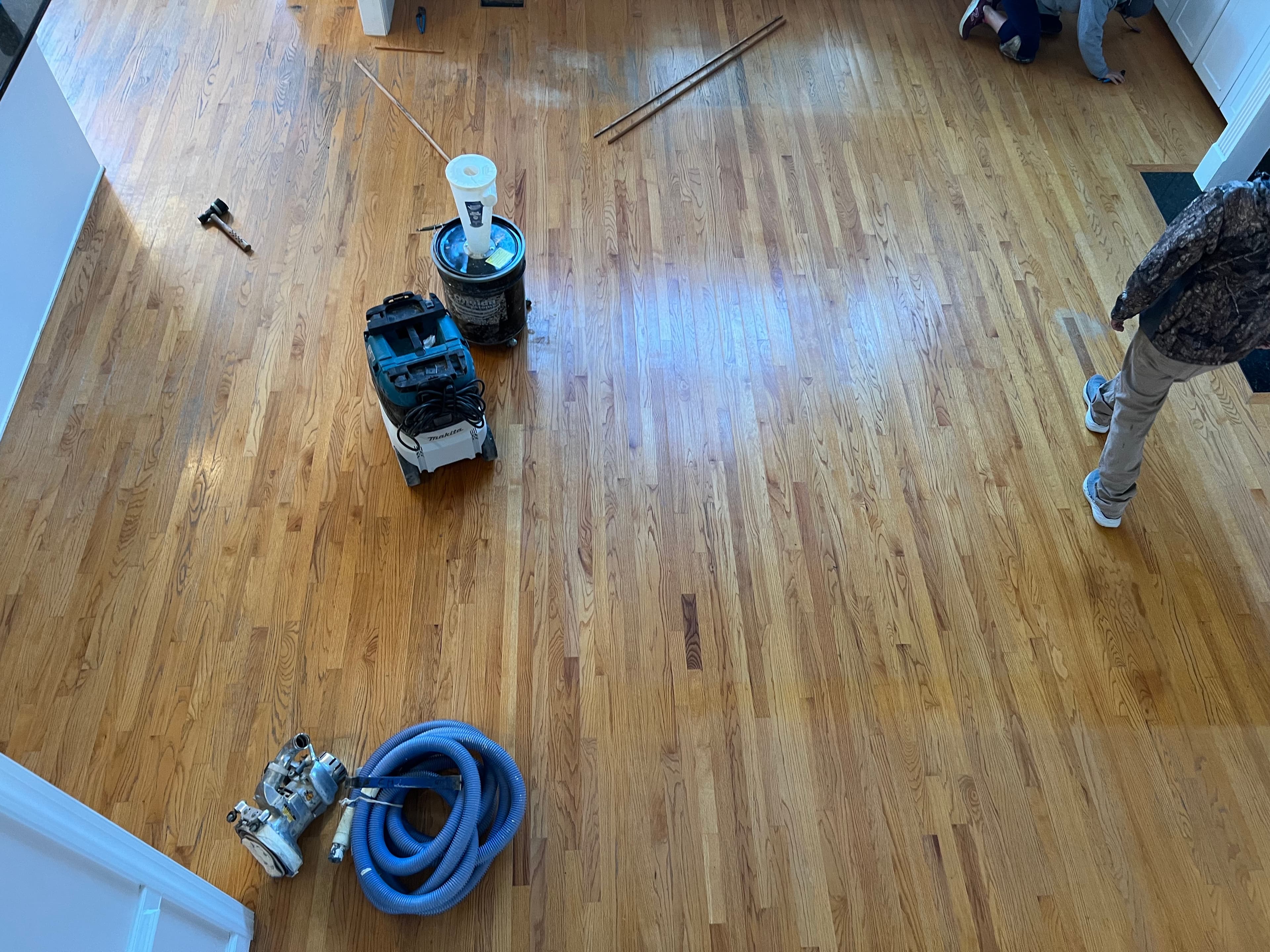 Overhead view of worn orange-amber red oak floors before refinishing in Austin Pond Clayton NC, sanding equipment staged in center of room