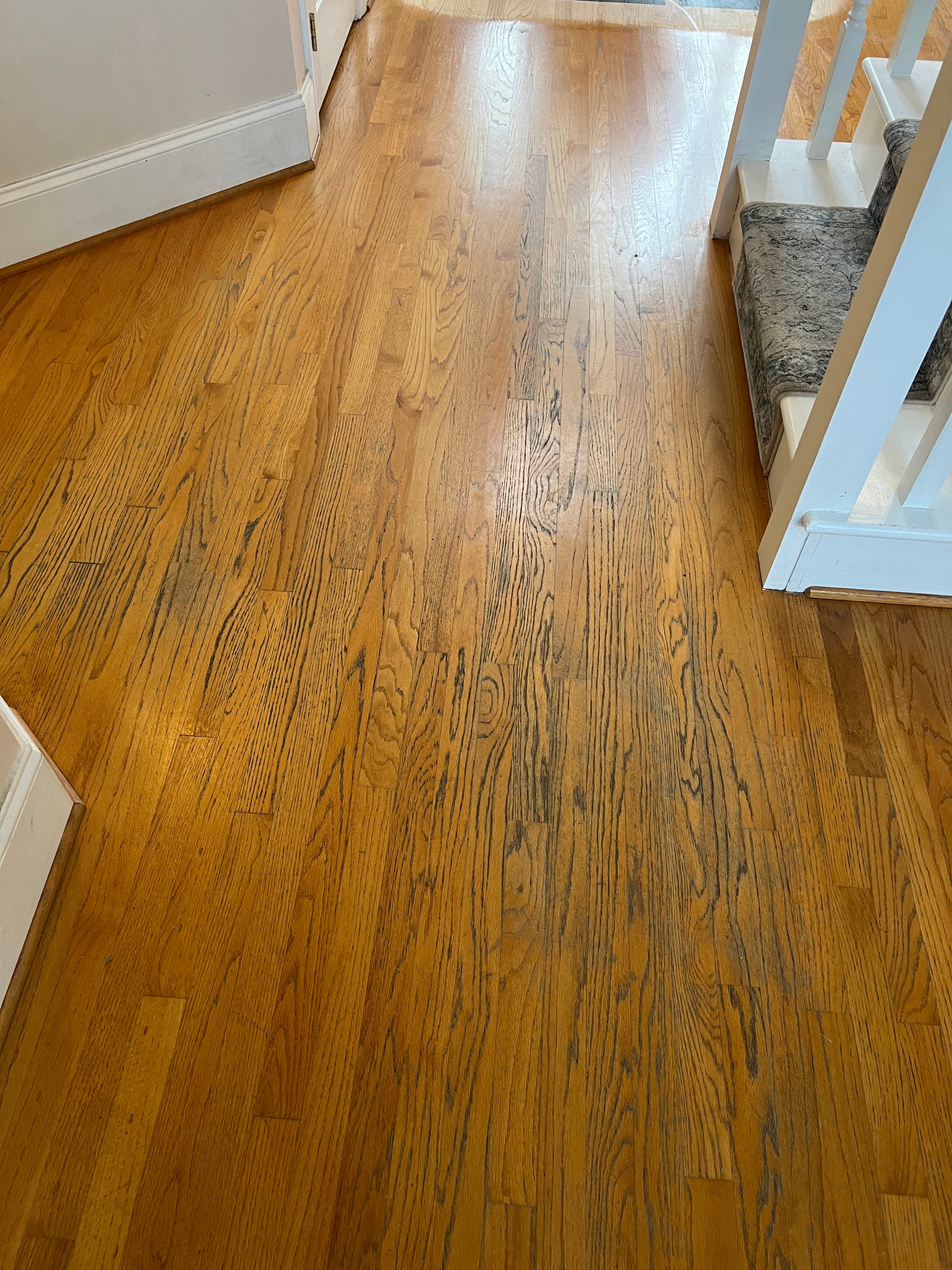 Worn amber red oak floors near staircase in Austin Pond Clayton NC, orange original finish heavily trafficked and worn