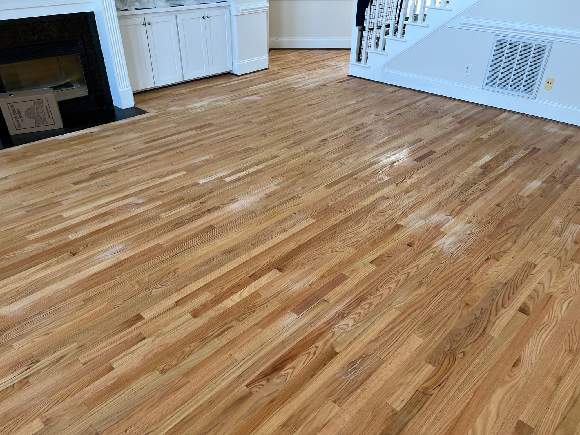 Water popped red oak floor in Austin Pond Clayton NC, fully sanded and wet from water popping before custom hardwax oil application, open plan living room with fireplace and staircase