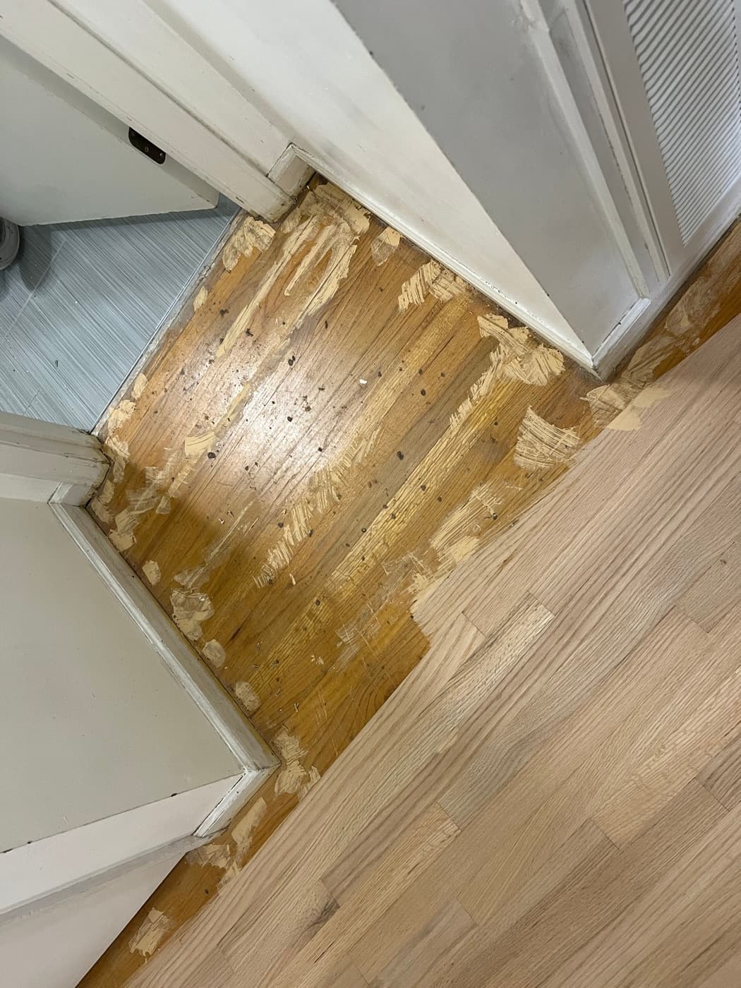 Wood putty repairs at doorway threshold on red oak floor during refinishing prep in Knightdale NC