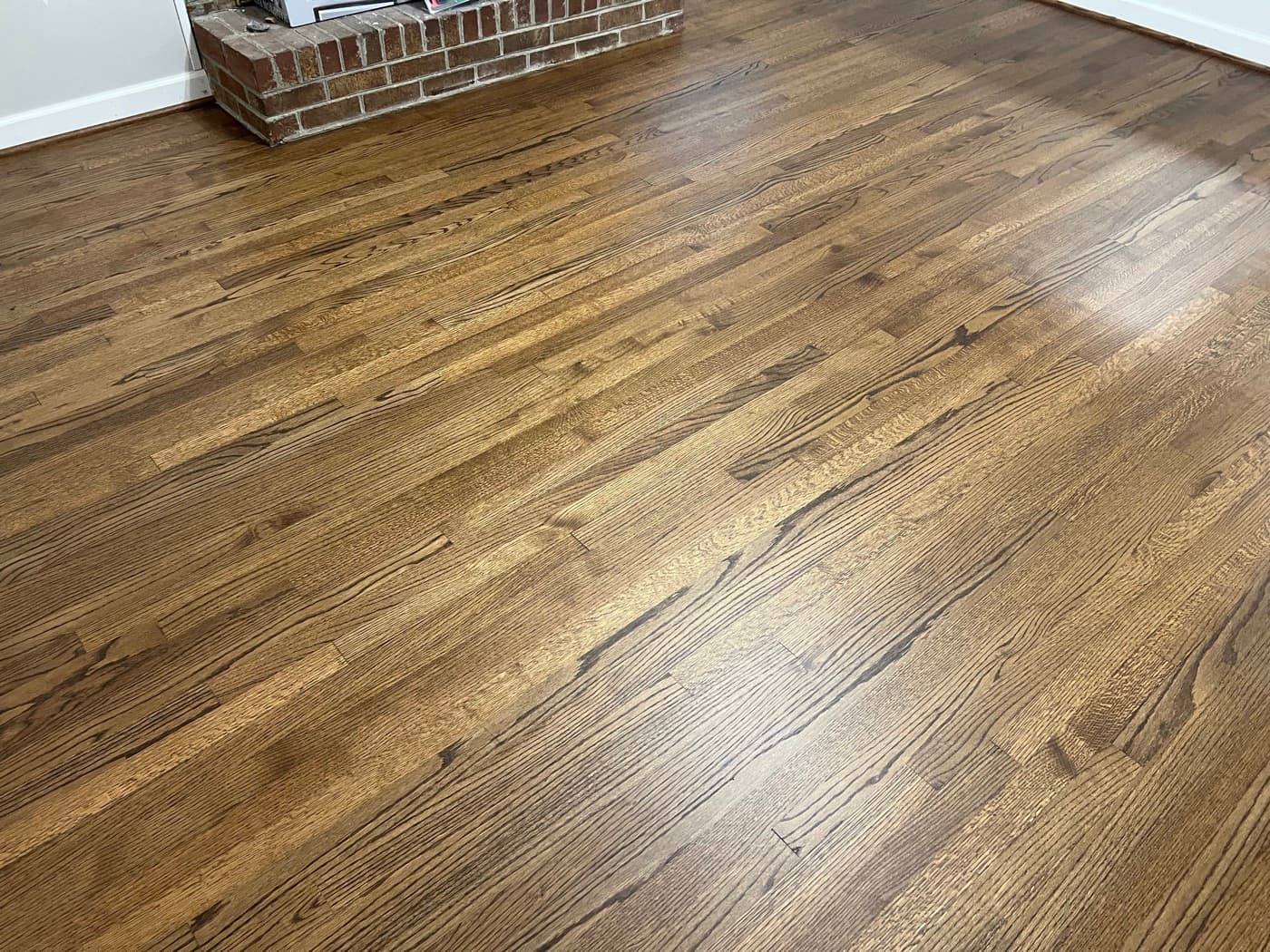 Finished red oak floors with DuraSeal Provincial stain and Bona Mega One in Downtown Knightdale NC, living room with original brick fireplace