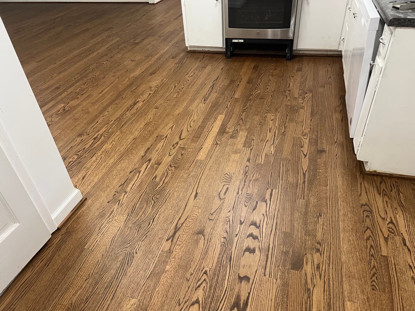 Finished red oak kitchen floor with DuraSeal Provincial stain and Bona Mega One, white cabinets and stainless appliances in Knightdale NC