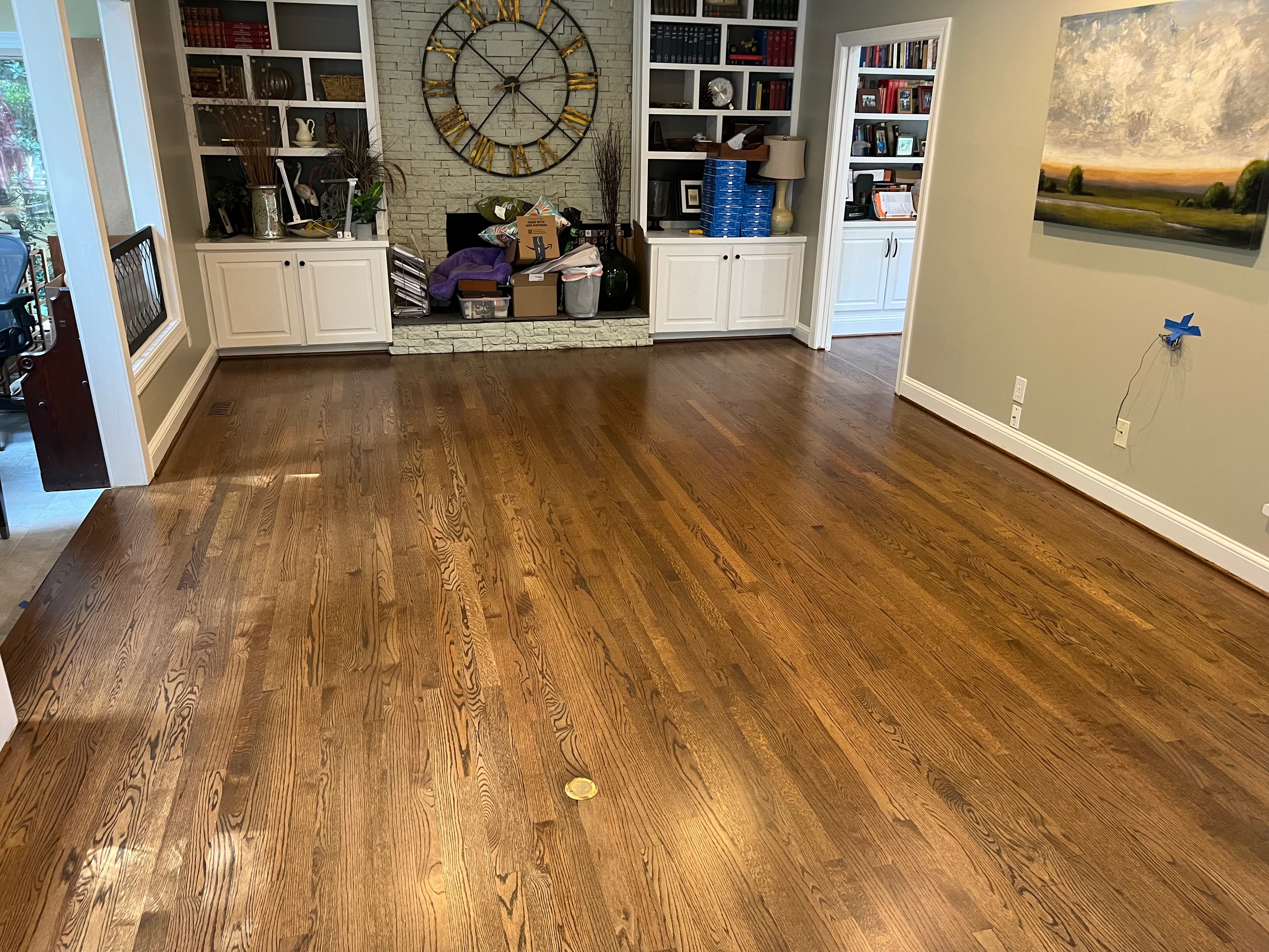 Finished 3.25 inch red oak floors with custom blended stain and Bona Traffic HD in Lochmere Cary NC, living room with built-in bookshelves and stone fireplace