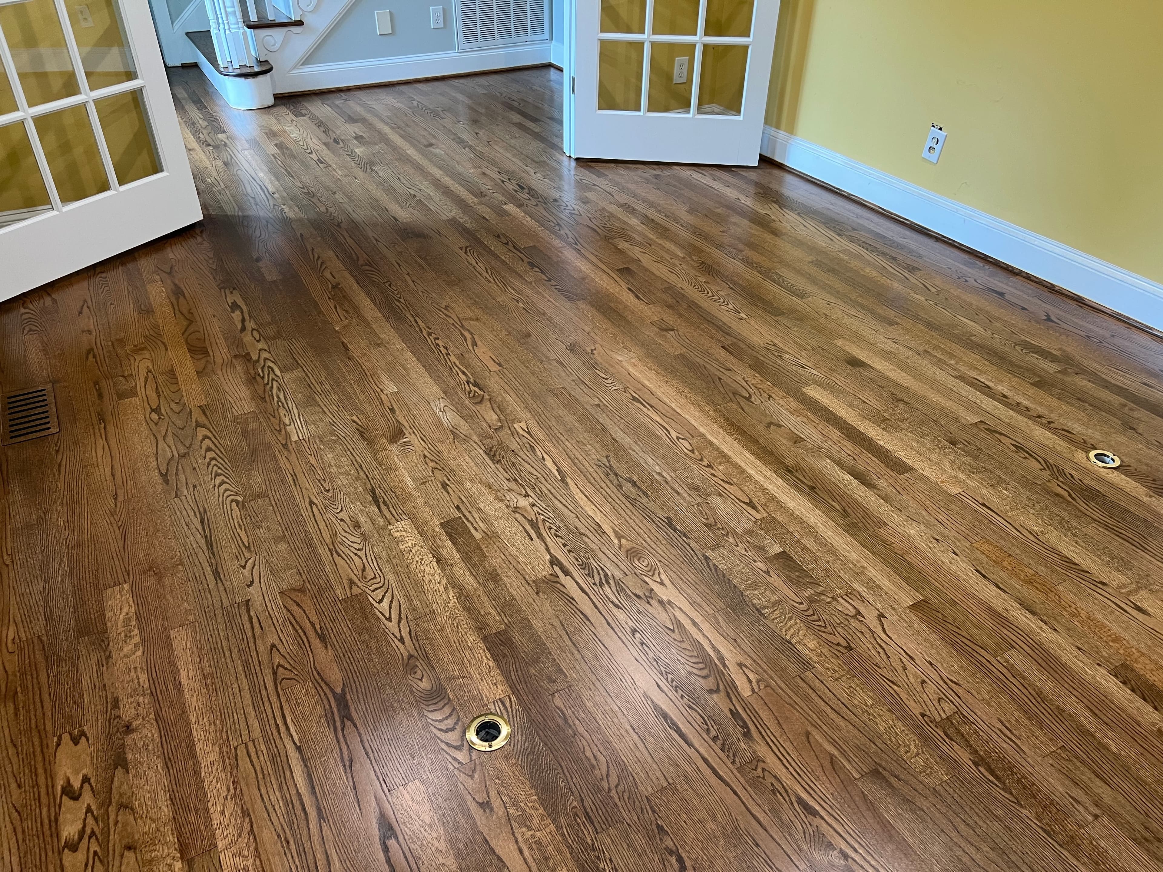 Finished red oak floors showing custom flush-mount hardwood vents in Lochmere Cary NC, two vents visible flush with floor surface near French doors