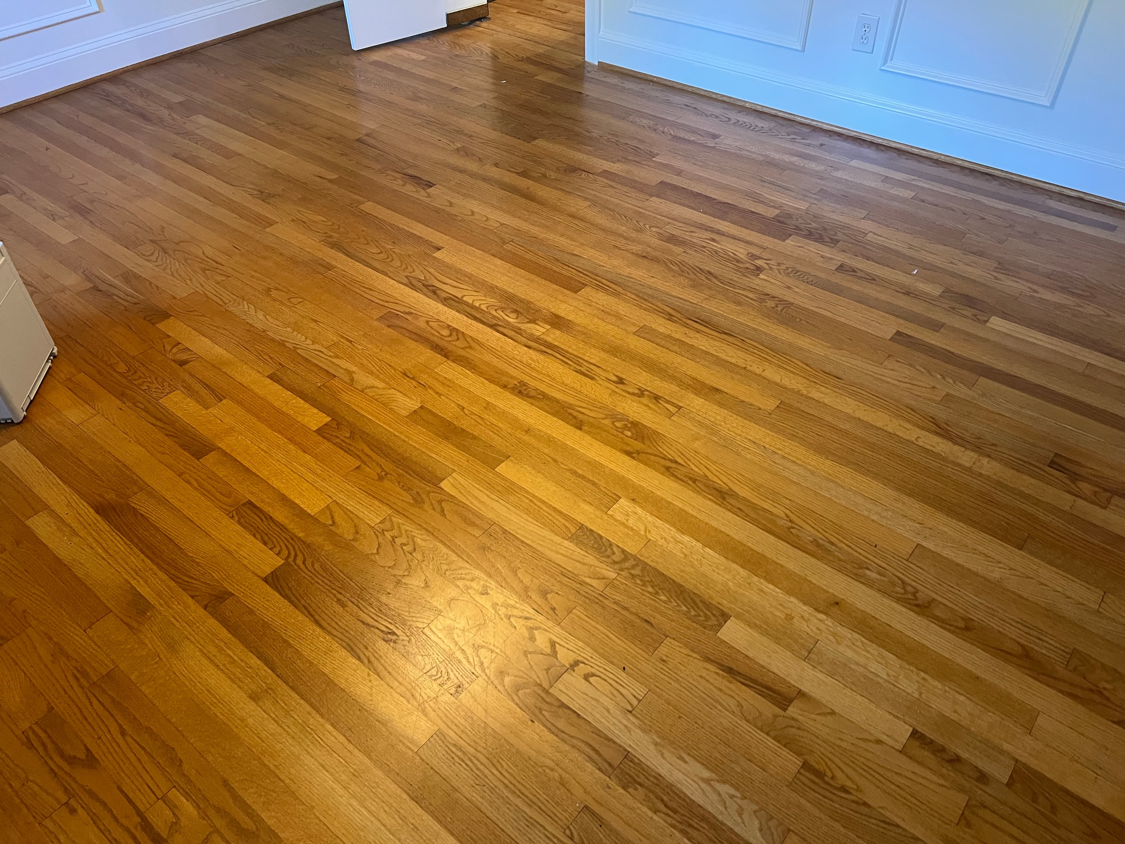 Worn and ambered 3.25 inch red oak floors before refinishing in Lochmere Cary NC, full room view showing uneven finish and traffic wear