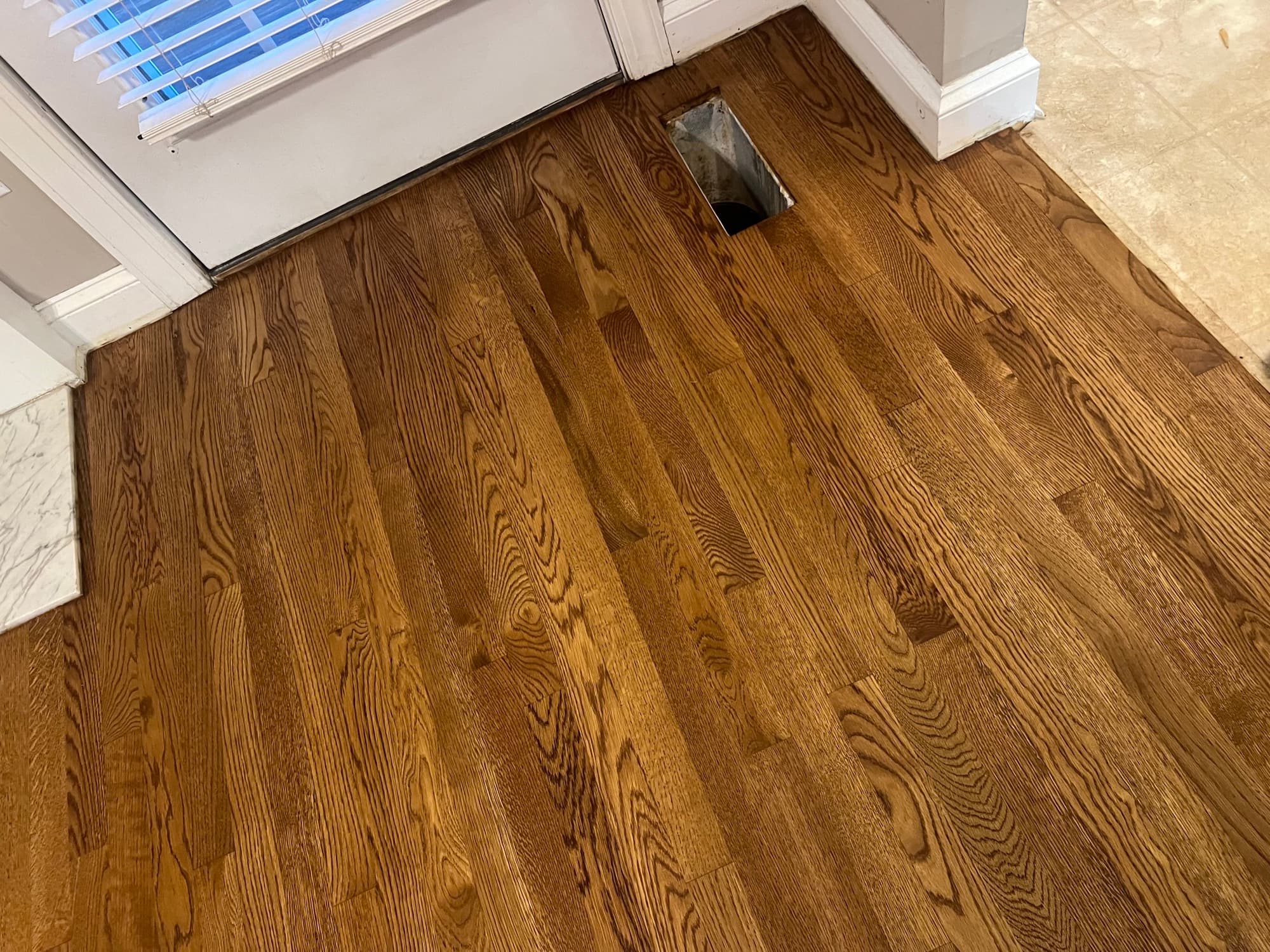 Finished red oak floors with DuraSeal Provincial near kitchen transition in Wilson NC, grain detail with marble countertop visible