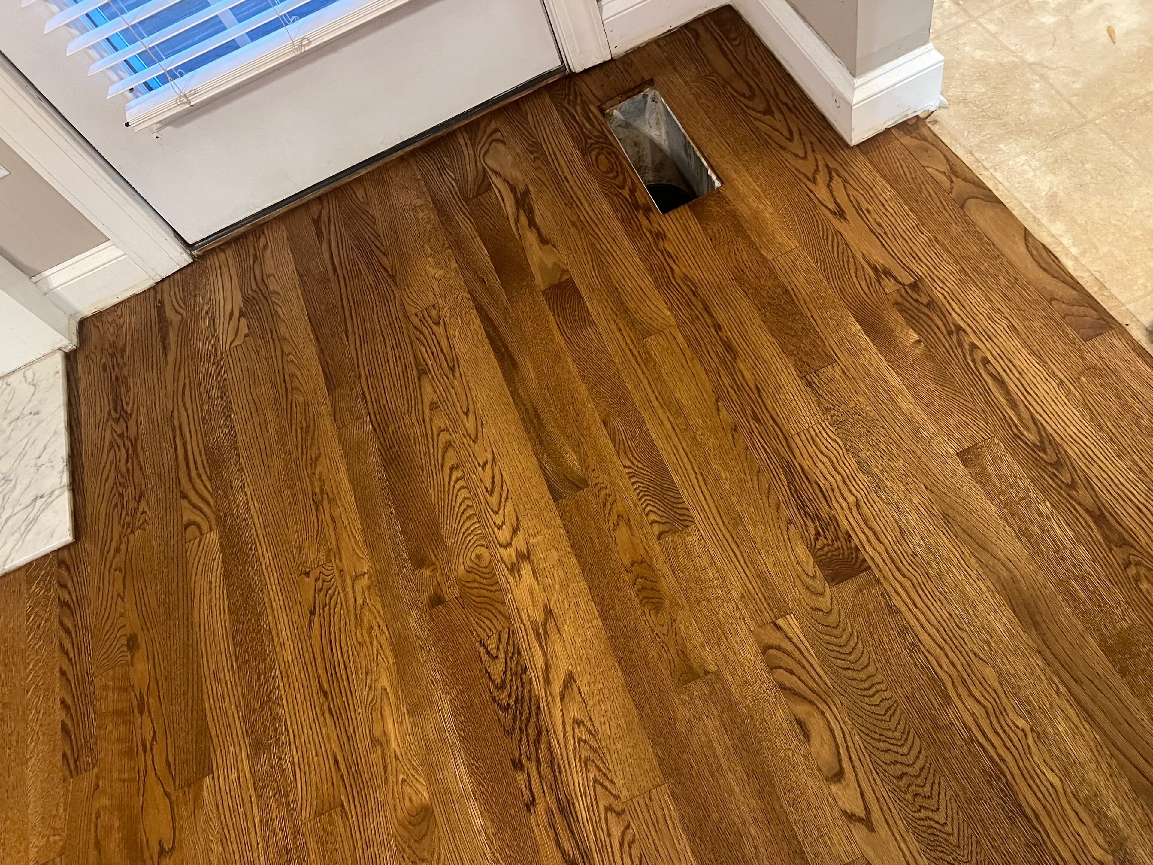 Finished red oak floors with DuraSeal Provincial near kitchen transition in Wilson NC, grain detail with marble countertop visible