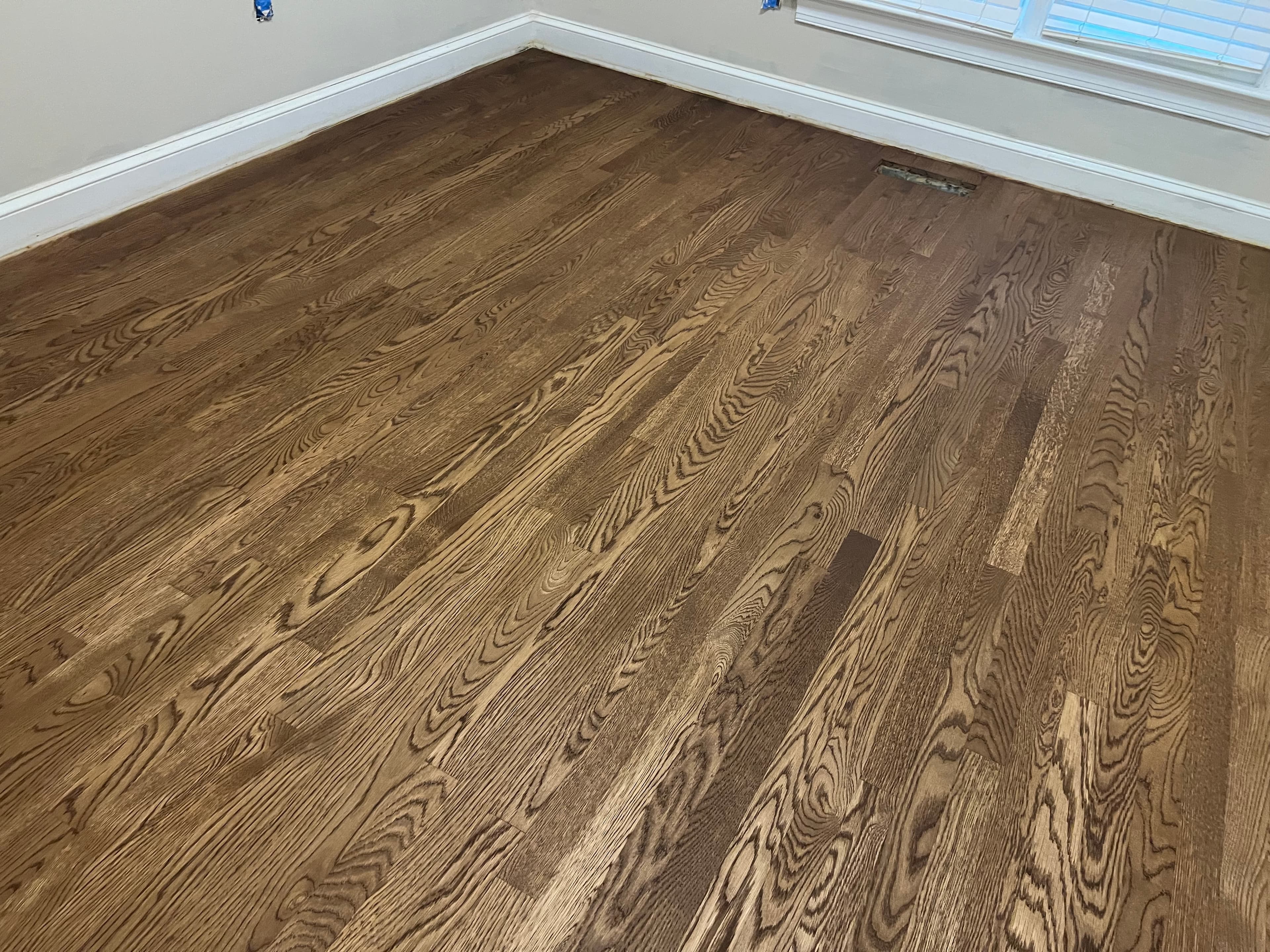Finished red oak floors with DuraSeal Provincial in corner room Wilson NC, warm brown tone throughout with natural window light