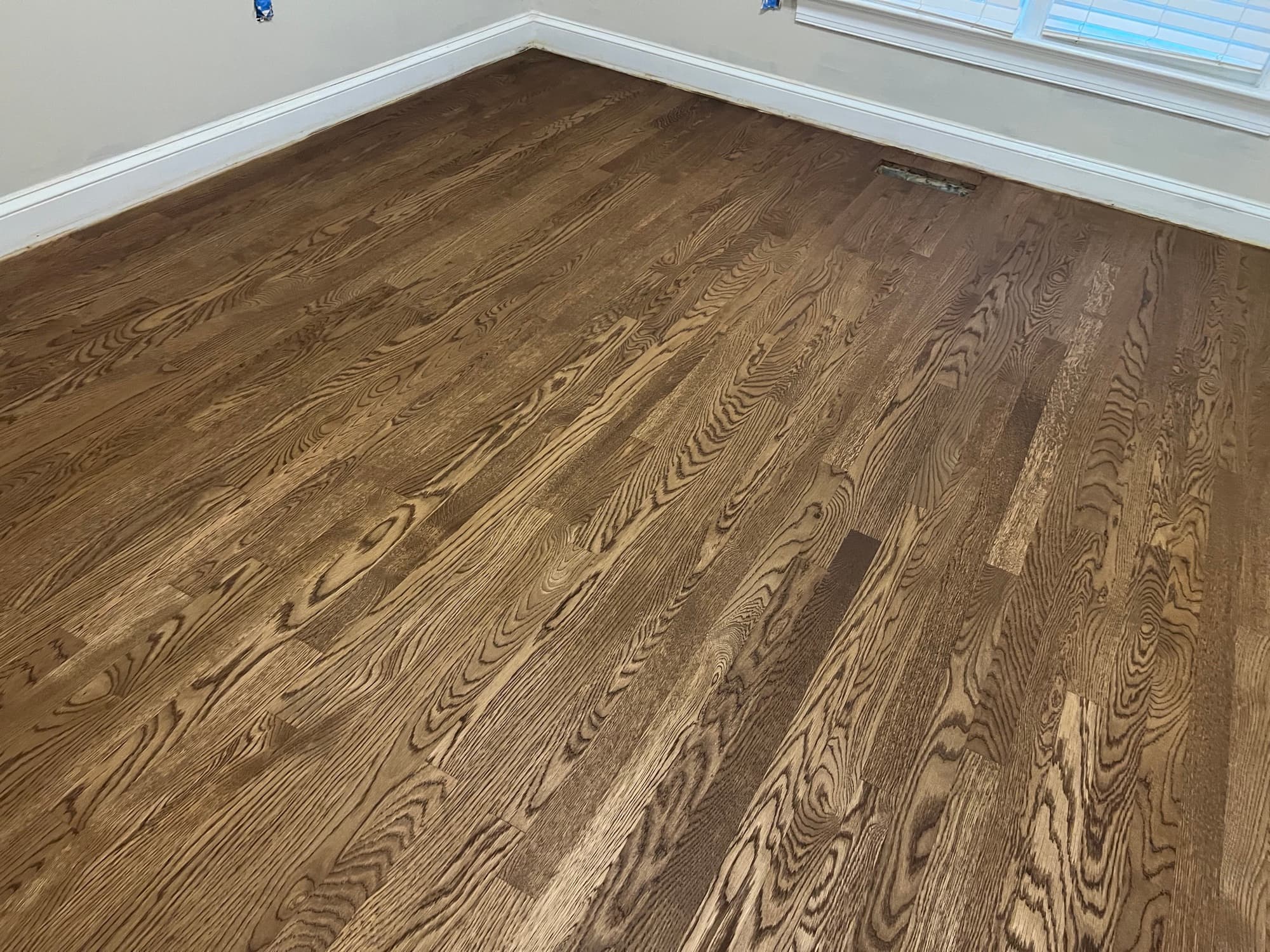 Finished red oak floors with DuraSeal Provincial in corner room Wilson NC, warm brown tone throughout with natural window light