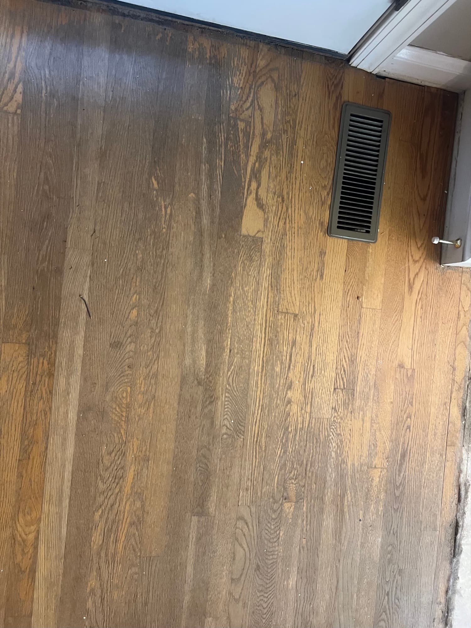 Severely worn red oak floor near baseboard in Wilson NC before refinishing, finish worn through completely showing bare wood