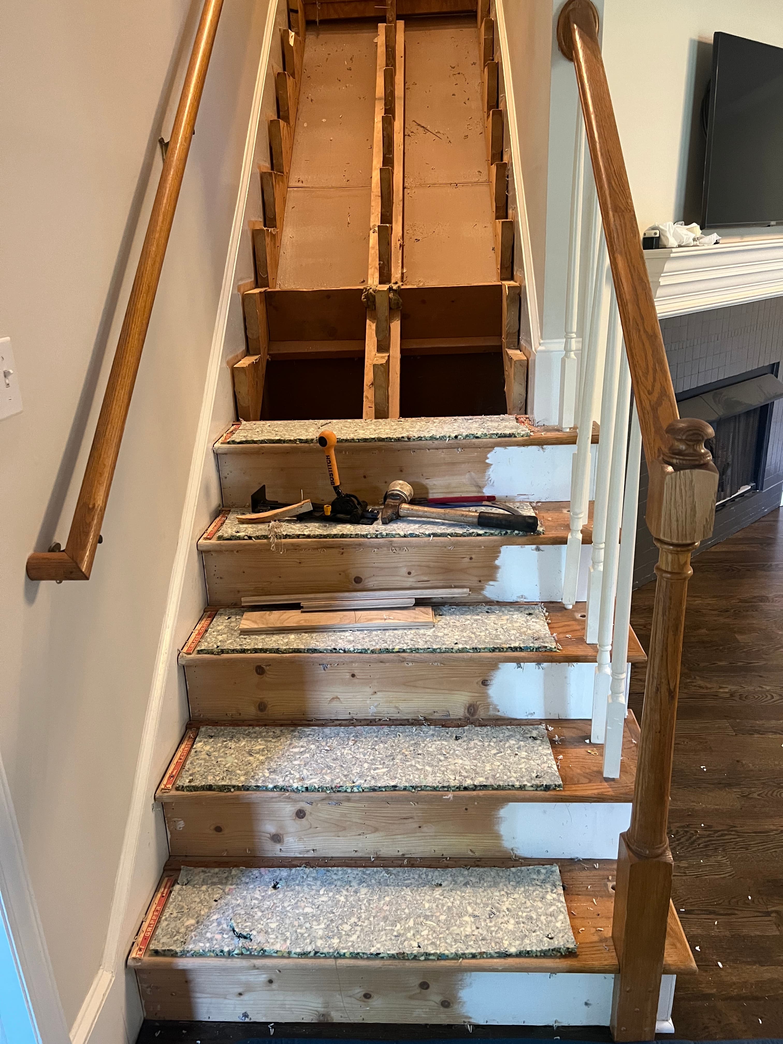 Staircase during carpet removal in North Fort Clayton NC, old carpet and pad stripped exposing pine stair structure, carpet remnants and tack strips visible