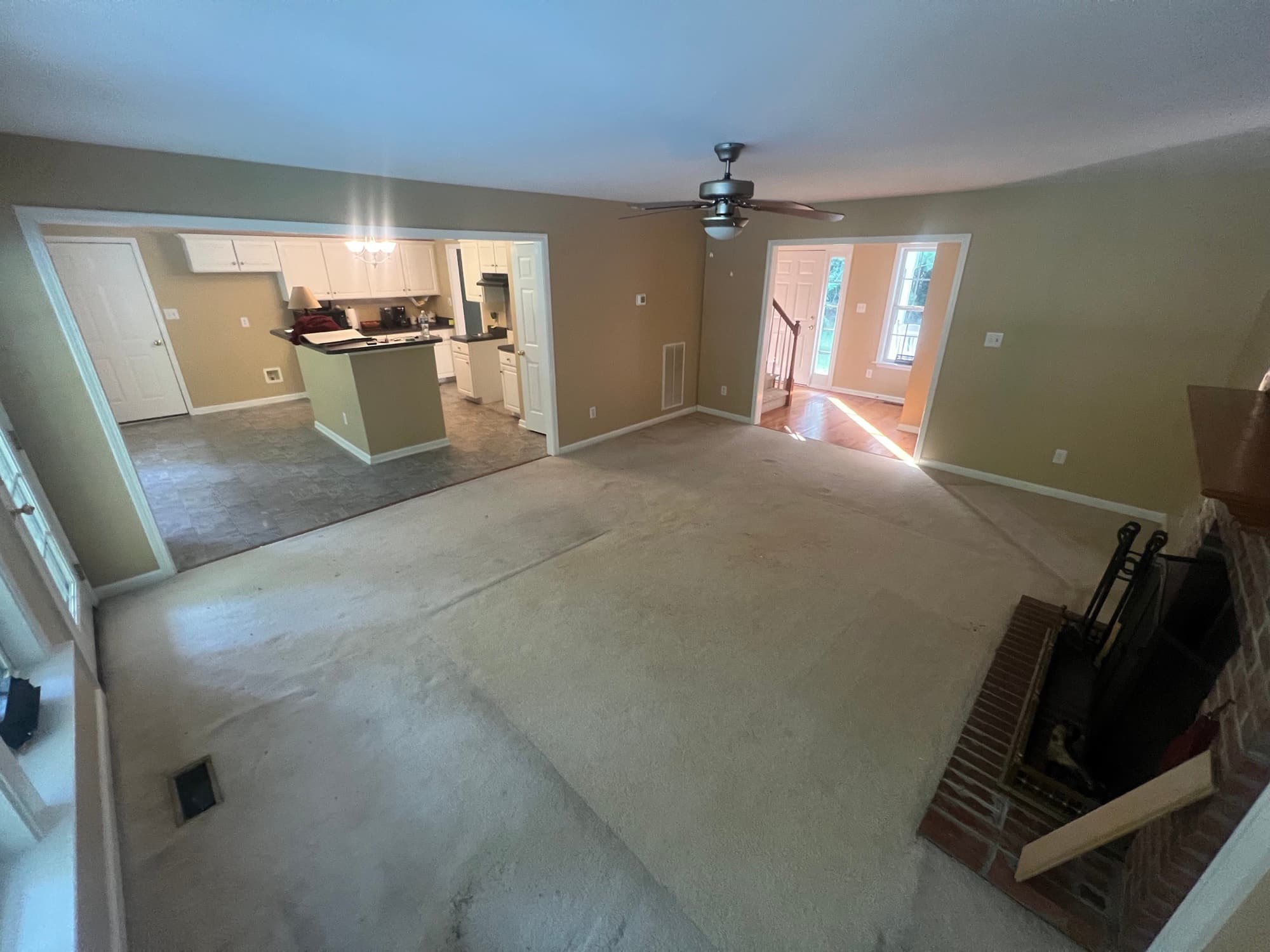 Living room with carpet and kitchen with vinyl tile before white oak installation in Westlake Wendell NC