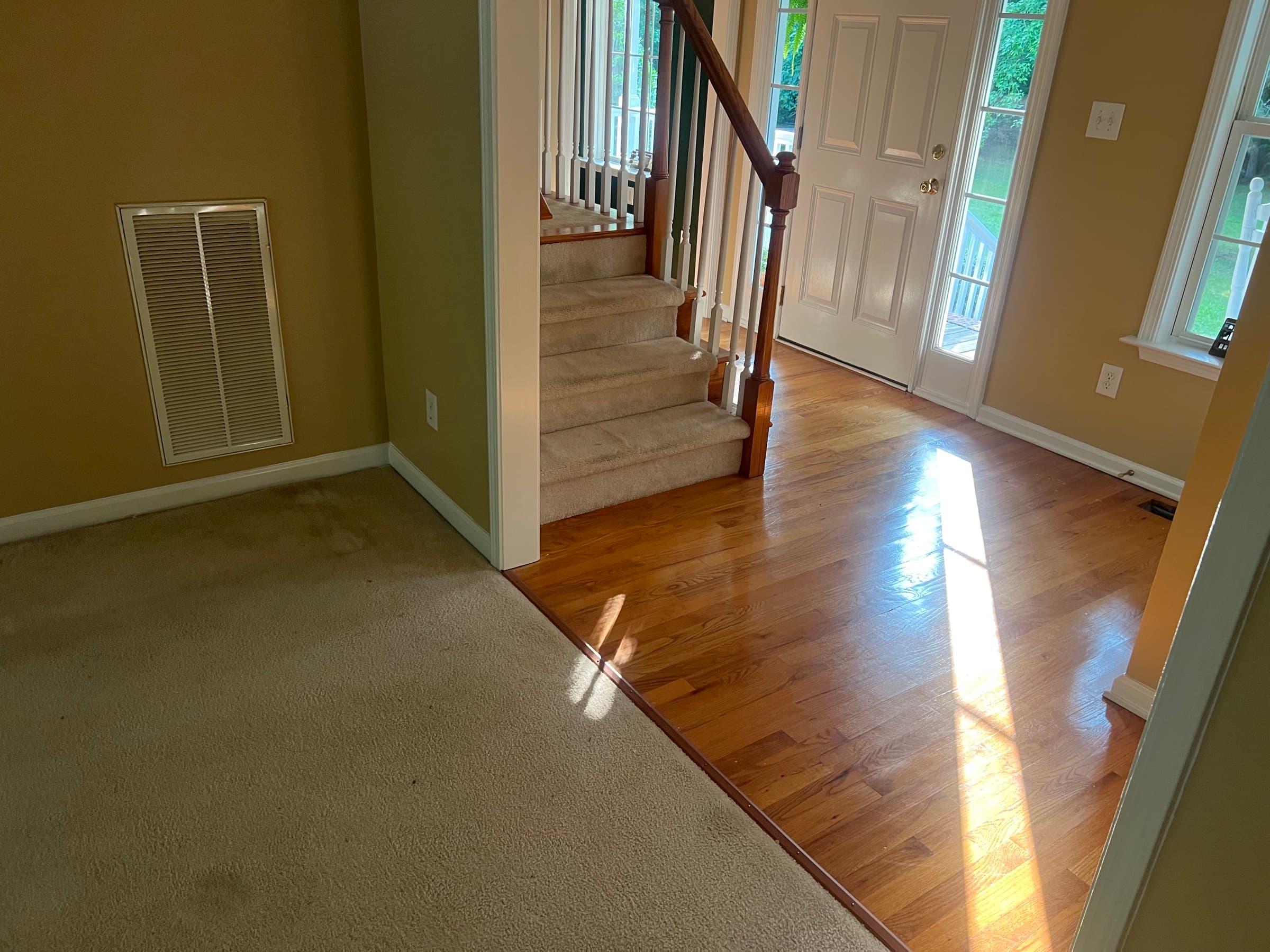 Foyer with original 2.25 inch red oak hardwood and carpeted stairs before demo in Westlake Wendell NC
